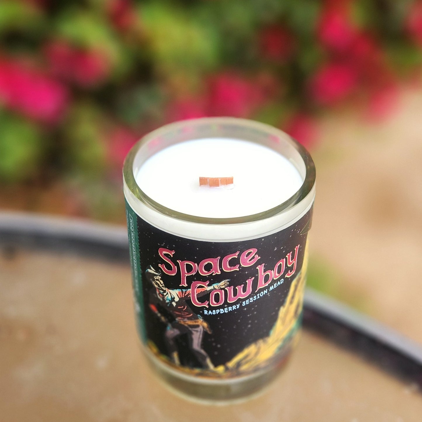 Eco-friendly "Space Cowboy" candle crafted in a recycled glass bottle, topped with a natural wooden wick and filled with clean-burning coconut soy wax.
