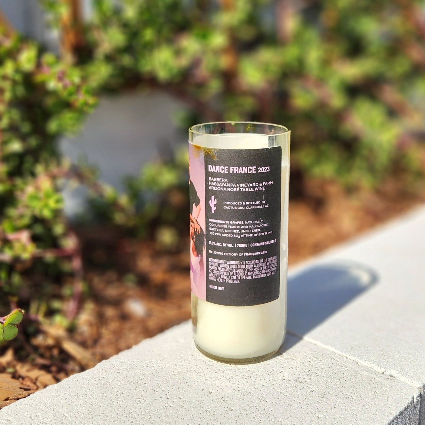 Back label view of a sustainable, handmade candle in an upcycled Arizona wine bottle, highlighting its vineyard origin and unique dedication.