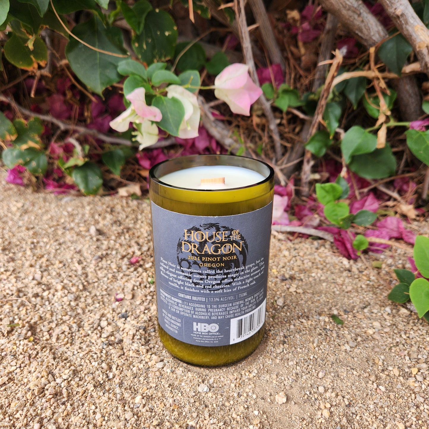 Eco-friendly candle hand-poured into a recycled wine bottle featuring the House of the Dragon wine label. The back label displays wine details from the 2021 Oregon Pinot Noir bottle, highlighting the sustainable reuse of branded glassware in this clean-burning coconut soy wax candle.