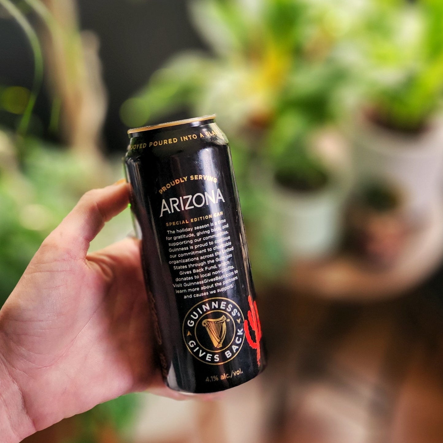 Hand holding a recycled stout can candle with a clean-burning wooden wick, proudly upcycled and labeled for Arizona support.