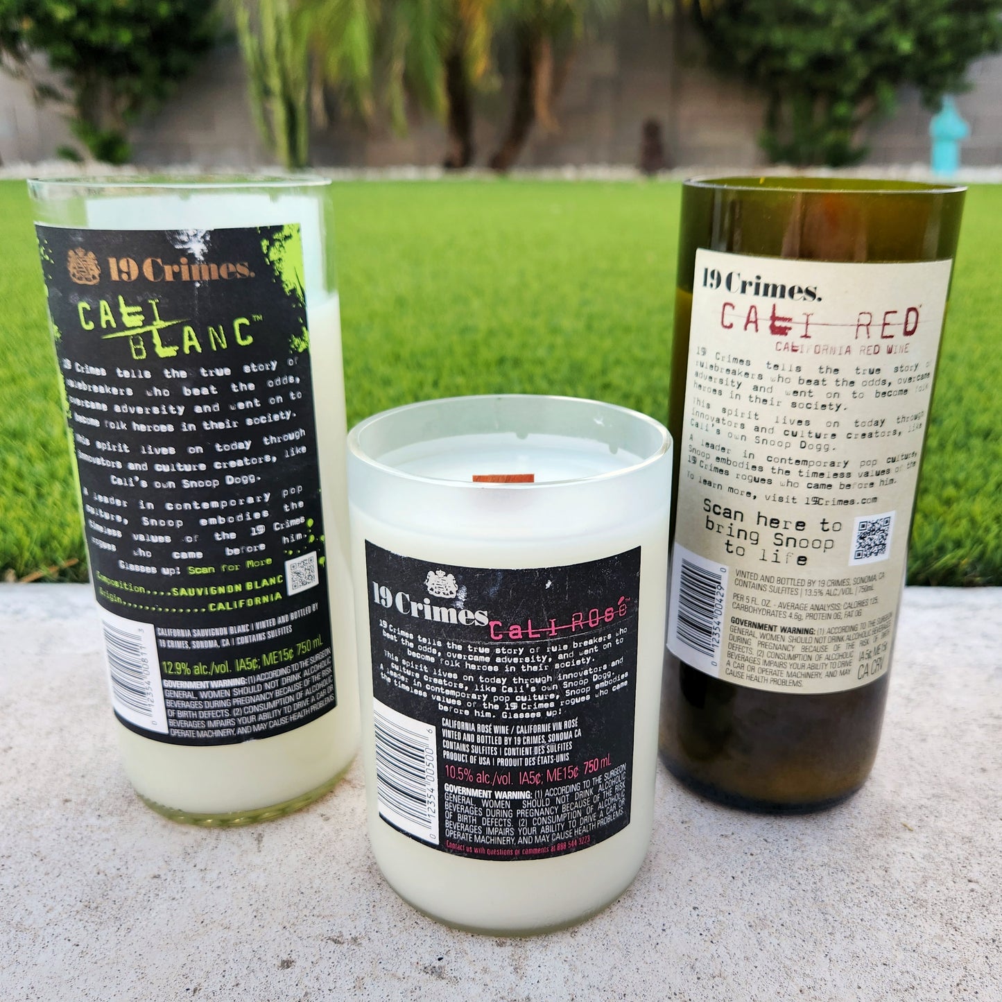 Back view of three upcycled 19 Crimes wine bottle candles—Cali Blanc, Cali Rosé, and Cali Red—highlighting original labels on each recycled bottle filled with coconut soy wax and wooden wicks.