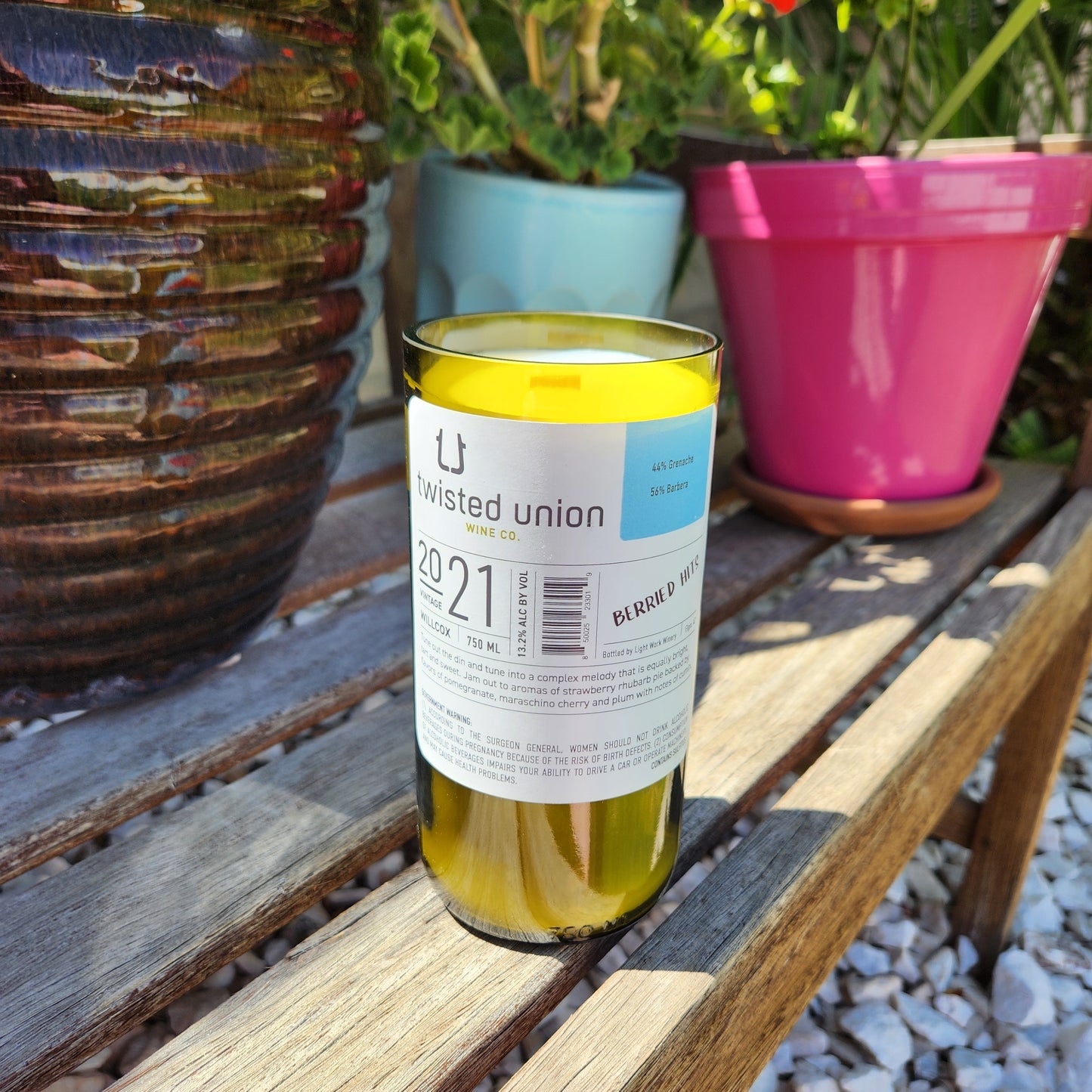 Back view of an eco-friendly wine bottle candle repurposed from a 2021 Twisted Union bottle, showcasing the label description. Hand poured with coconut soy wax and a wooden wick, this recycled candle highlights Cactus Vine's commitment to sustainable craftsmanship.