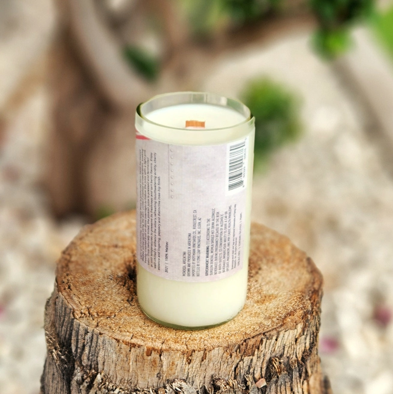 Back view of an upcycled wine bottle candle with a vintage-style label, showing the product details. The candle is filled with creamy white coconut soy wax and features a wooden wick, highlighting its eco-friendly, handmade appeal.