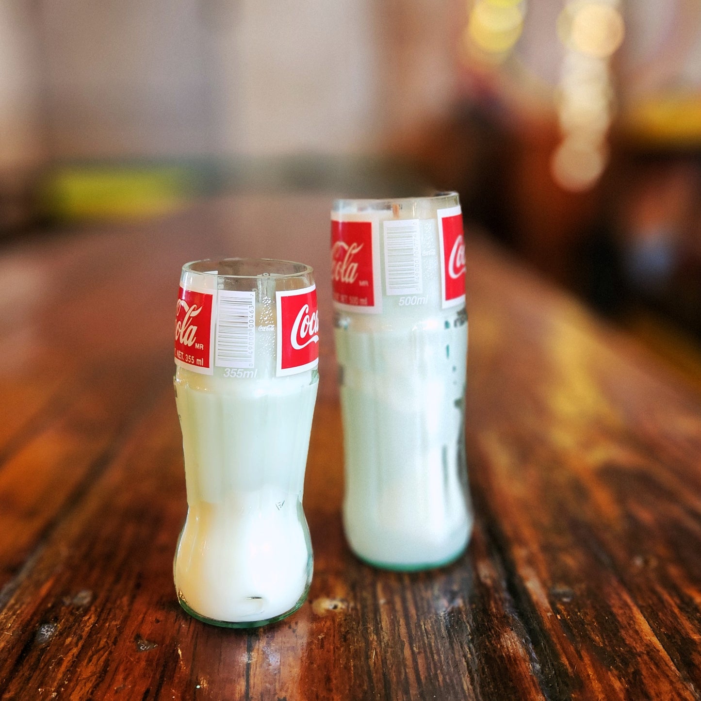 Back view of 355ml and 500ml Coca-Cola bottle candles, showing the UPC labels and capacity markings. Each candle is hand poured with coconut soy wax into a repurposed Coke bottle for a vintage yet sustainable vibe.