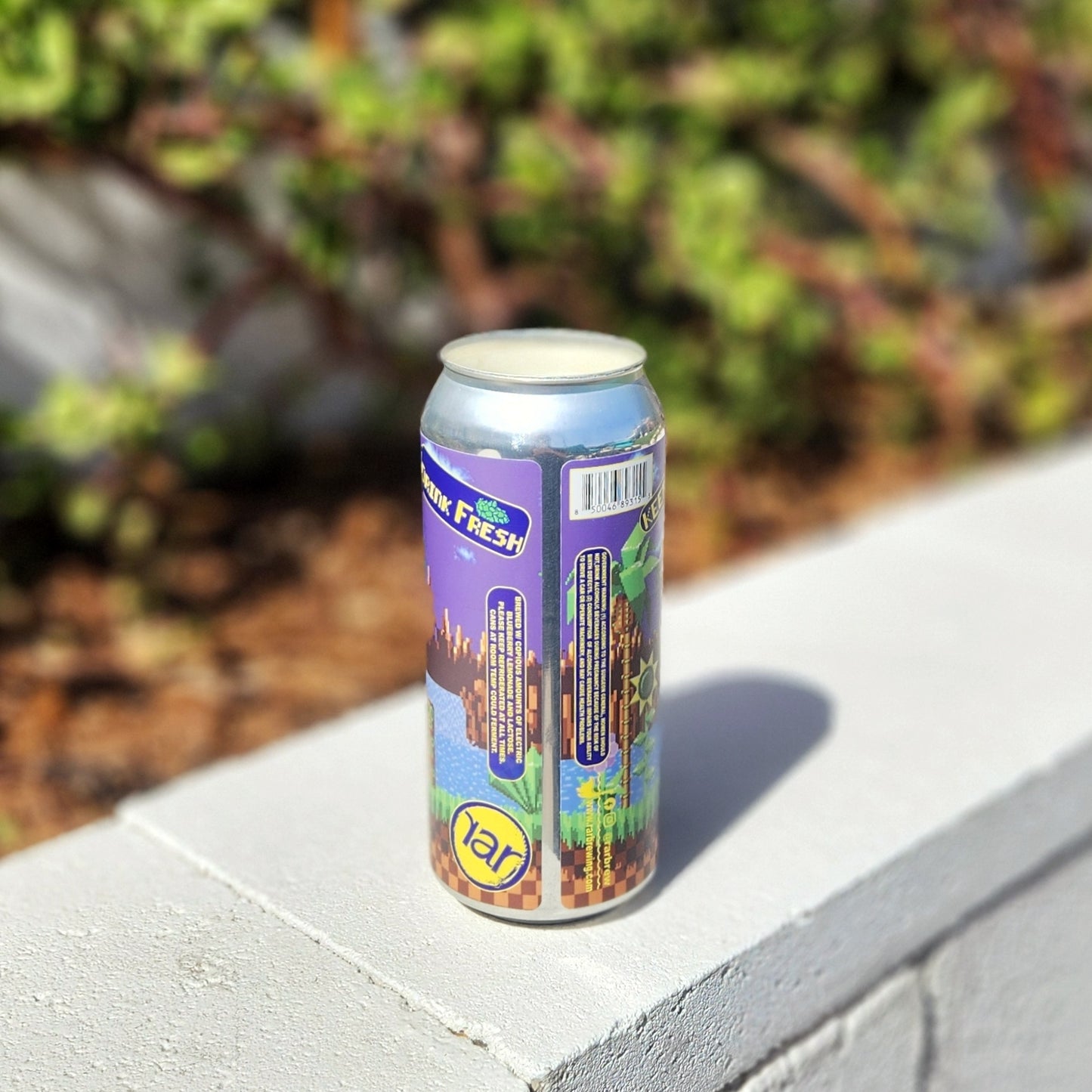 A hand-poured candle in a recycled beer can featuring a vibrant, nostalgic label inspired by retro video games. The eco-friendly candle is made with non-toxic coconut soy wax and a wooden wick, capturing attention with its colorful artwork and upcycled charm.