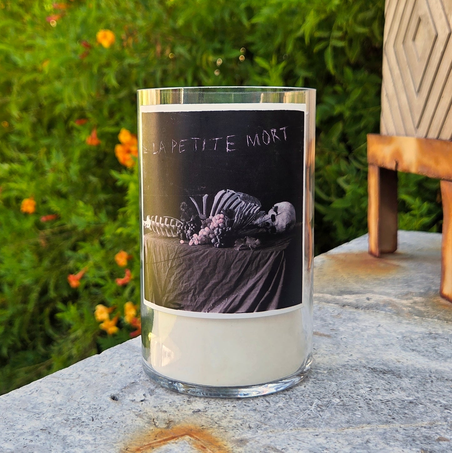 Front view of La Petite Mort wine bottle candle featuring skeleton artwork on the label, hand-poured with clean-burning coconut soy wax and wooden wick.