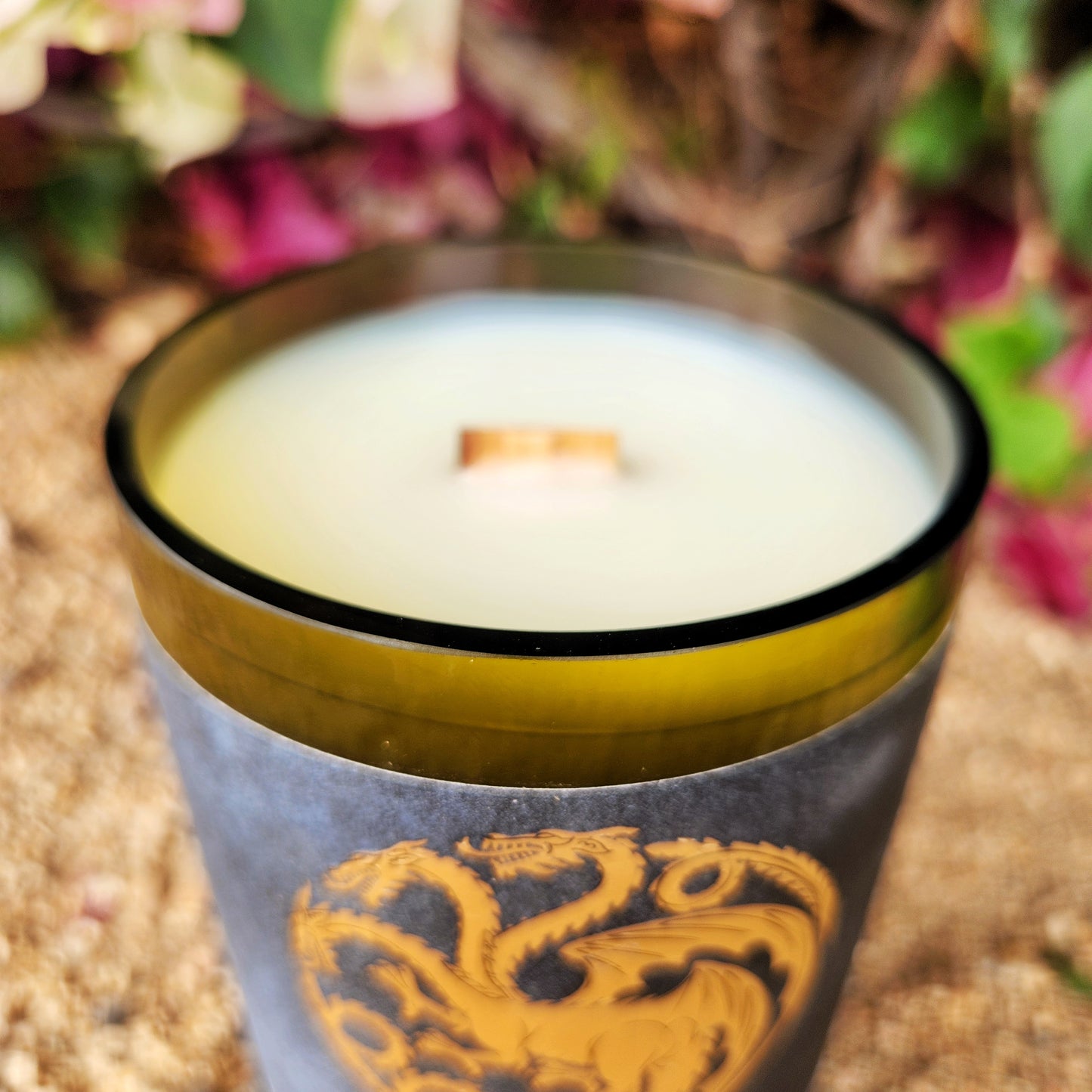 Close-up of the glossy rim and wooden wick of a hand-poured coconut soy wax candle in a recycled wine bottle, featuring a gold dragon label inspired by House of the Dragon. Eco-friendly and upcycled with a bold fantasy aesthetic.