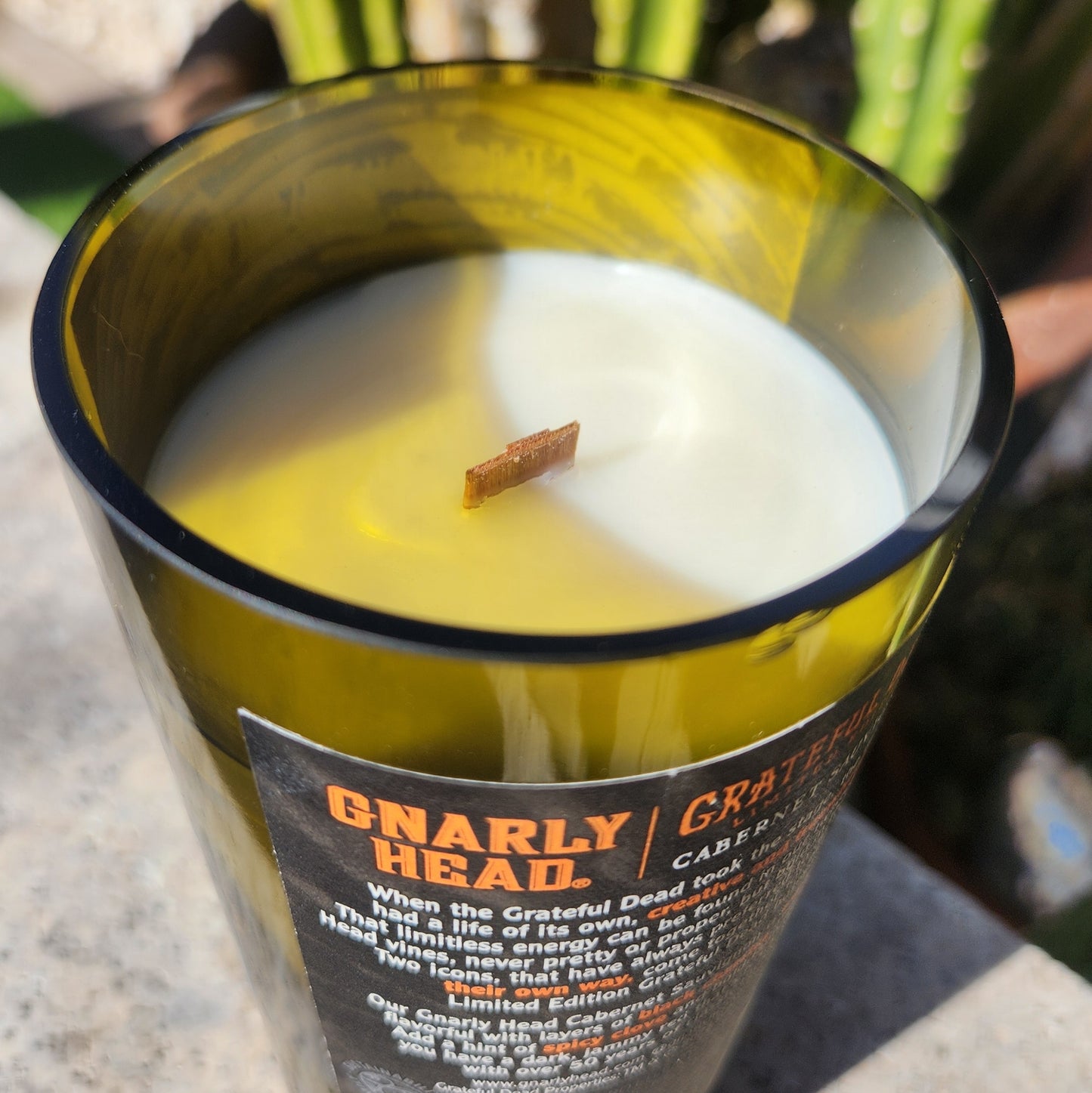 Close-up of the rim and label of the repurposed Grateful Dead bottle candle, showcasing the rich wax and wooden wick for a clean, aromatic burn.