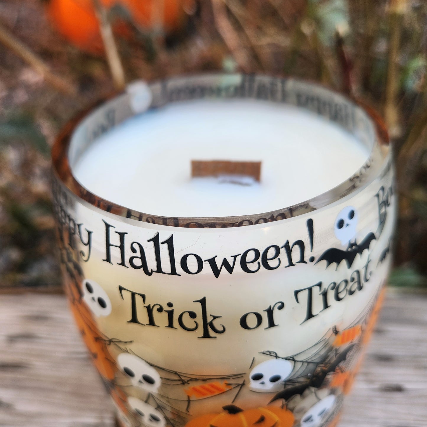 A hand-poured wine bottle candle made with non-toxic coconut soy wax and a wooden wick, featuring festive Halloween graphics like pumpkins, ghosts, and the phrases "Trick or Treat" and "Happy Halloween!" on the outer glass.