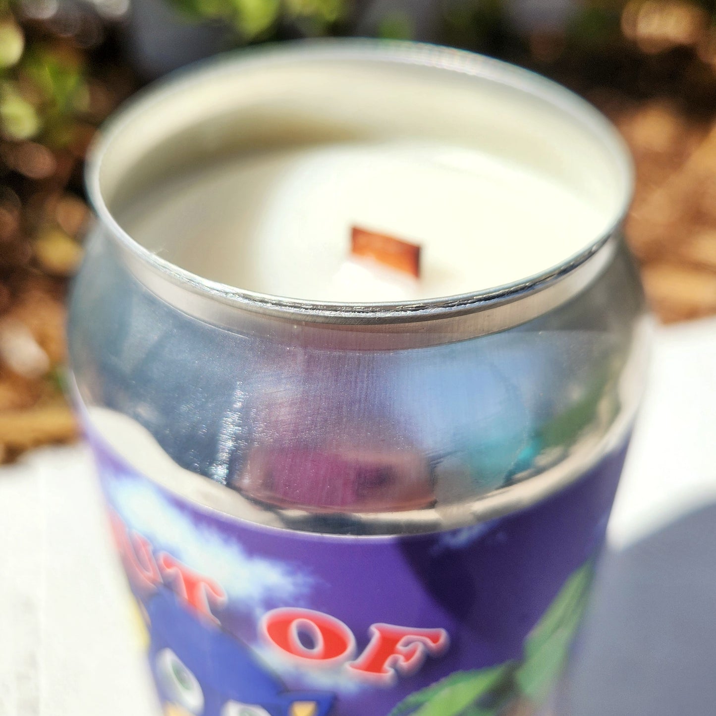Close-up of a non-toxic coconut soy wax candle with a wooden wick, housed in a shiny recycled beer can. The smooth silver rim adds a clean, modern contrast to the playful label, making this eco-conscious candle both bold and collectible.