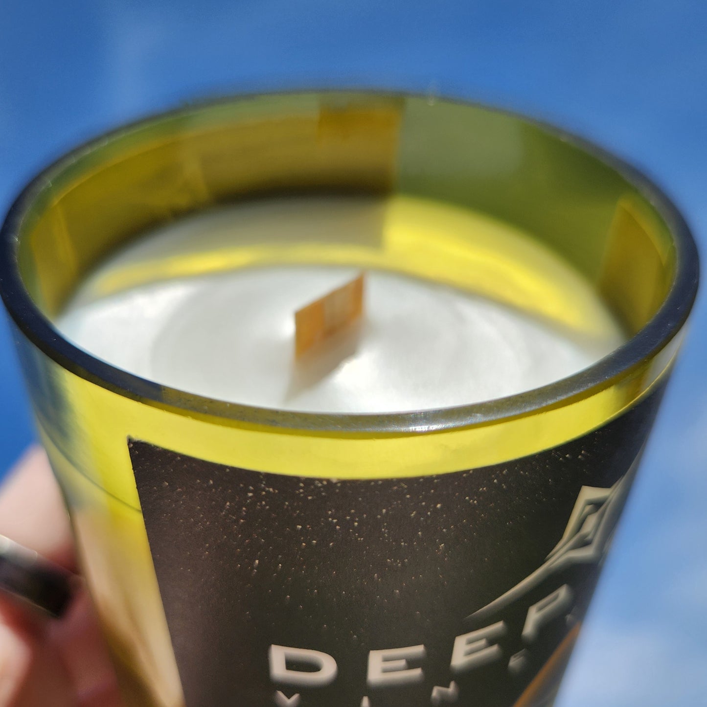 Close-up of the smooth rim and wooden wick of the Fusion wine bottle candle, revealing the creamy surface of the coconut soy wax. The upcycled bottle has a soft yellow tint and a luxury feel, ideal for eco-conscious candle lovers.