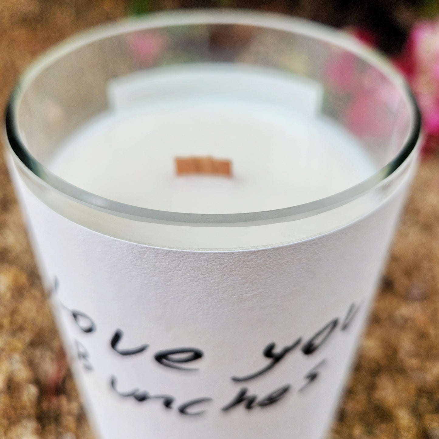 A close-up angled shot of a recycled wine bottle candle with a white label that reads “Love You Bunches.” The creamy coconut soy wax and centered wooden wick highlight the artisanal quality of this clean-burning, eco-friendly candle.