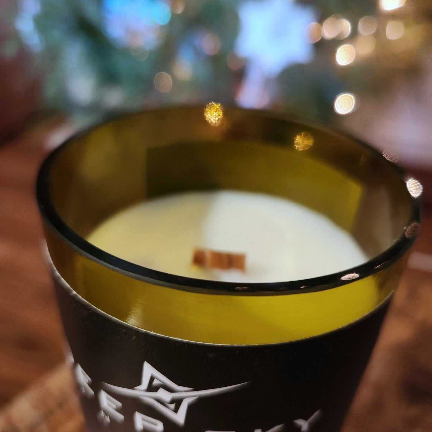 Close-up of a recycled Deep Sky Vineyard wine bottle candle with a polished rim, wooden wick, and warm bokeh lighting—highlighting the elegant upcycled design and festive feel.