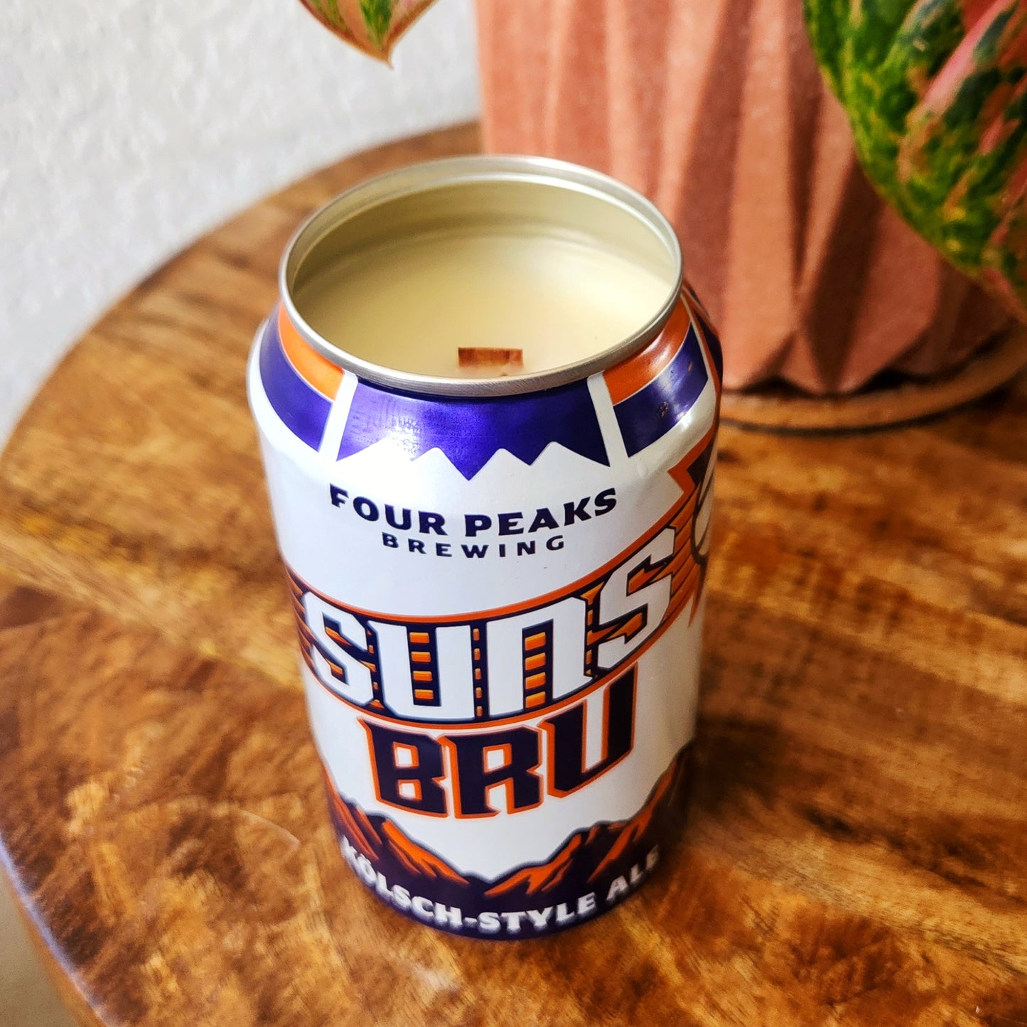 Close-up of a wooden wick candle hand-poured into a recycled Suns BRU beer can, featuring creamy white coconut soy wax and a smooth metal rim. The vibrant label showcases orange and purple graphics, turning this eco-friendly upcycled candle into a fun tribute to Arizona sports and beer culture.