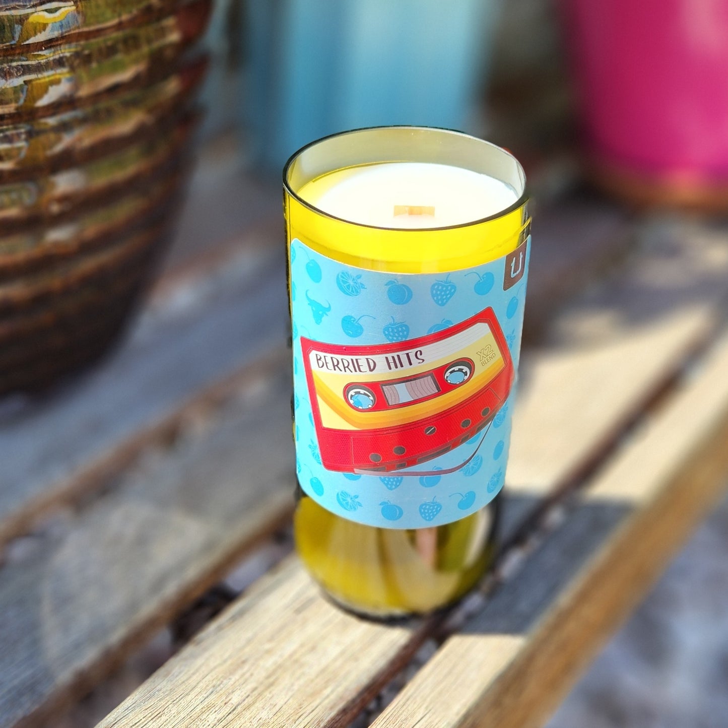 Angled view of a wooden wick peeking through smooth white coconut soy wax inside a recycled Twisted Union wine bottle candle. This eco-friendly candle features a clean, curved glass rim and colorful label design, handcrafted by Cactus Vine Candles.