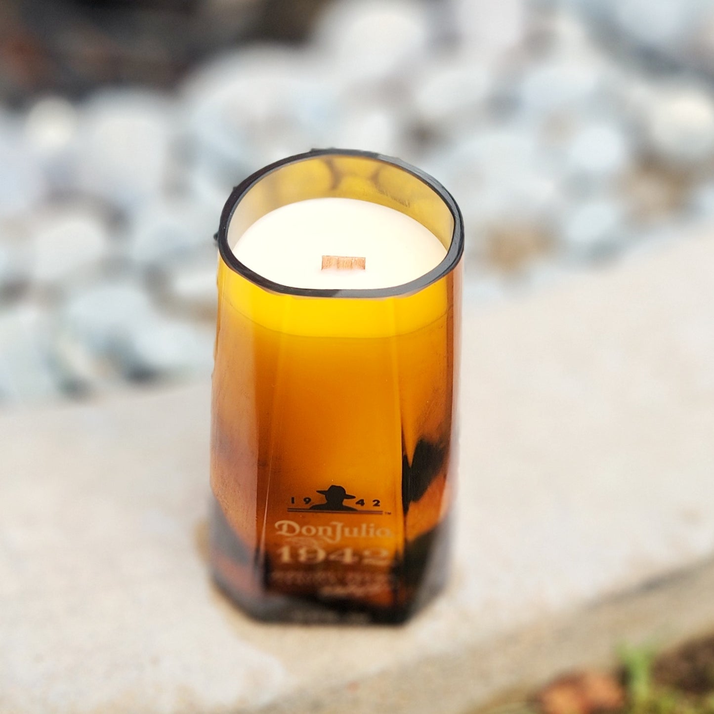 Angled view of a Don Julio 1942 branded liquor bottle transformed into a luxury candle with a wooden wick and natural wax blend for a healthy, sustainable glow.