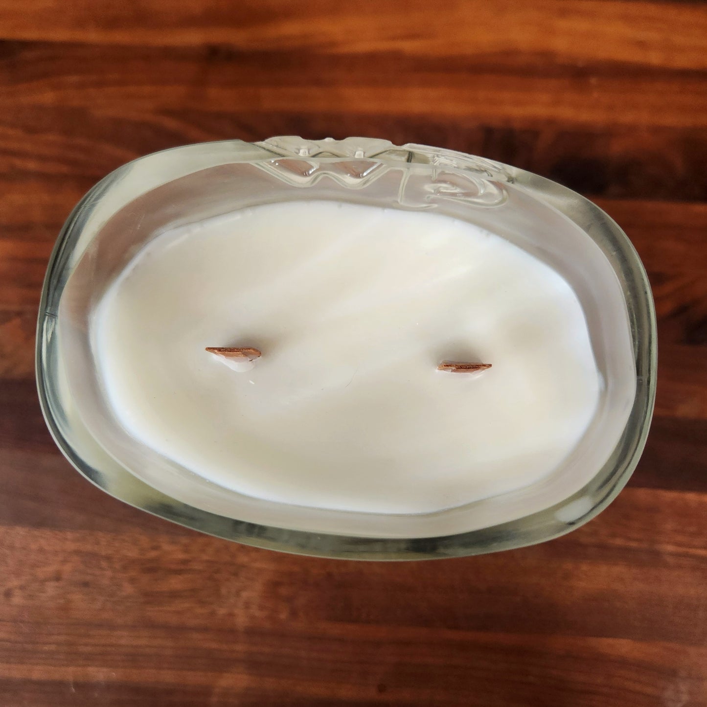 Top view of an eco-friendly two-wick candle made from a repurposed WhistlePig PiggyBack rye whiskey glass, filled with creamy white coconut soy wax and two evenly spaced wooden wicks for a strong, even burn.