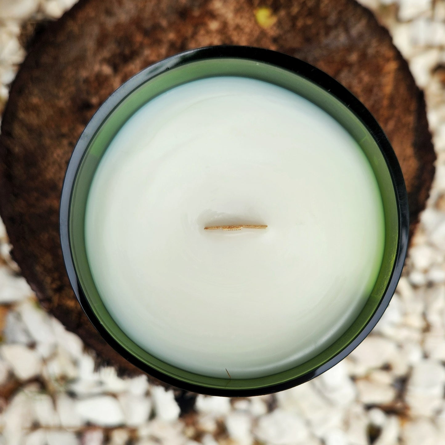 Top-down view of an eco-friendly coconut soy wax candle with a wooden wick, hand poured into a recycled green wine bottle featuring the Curator wine label.