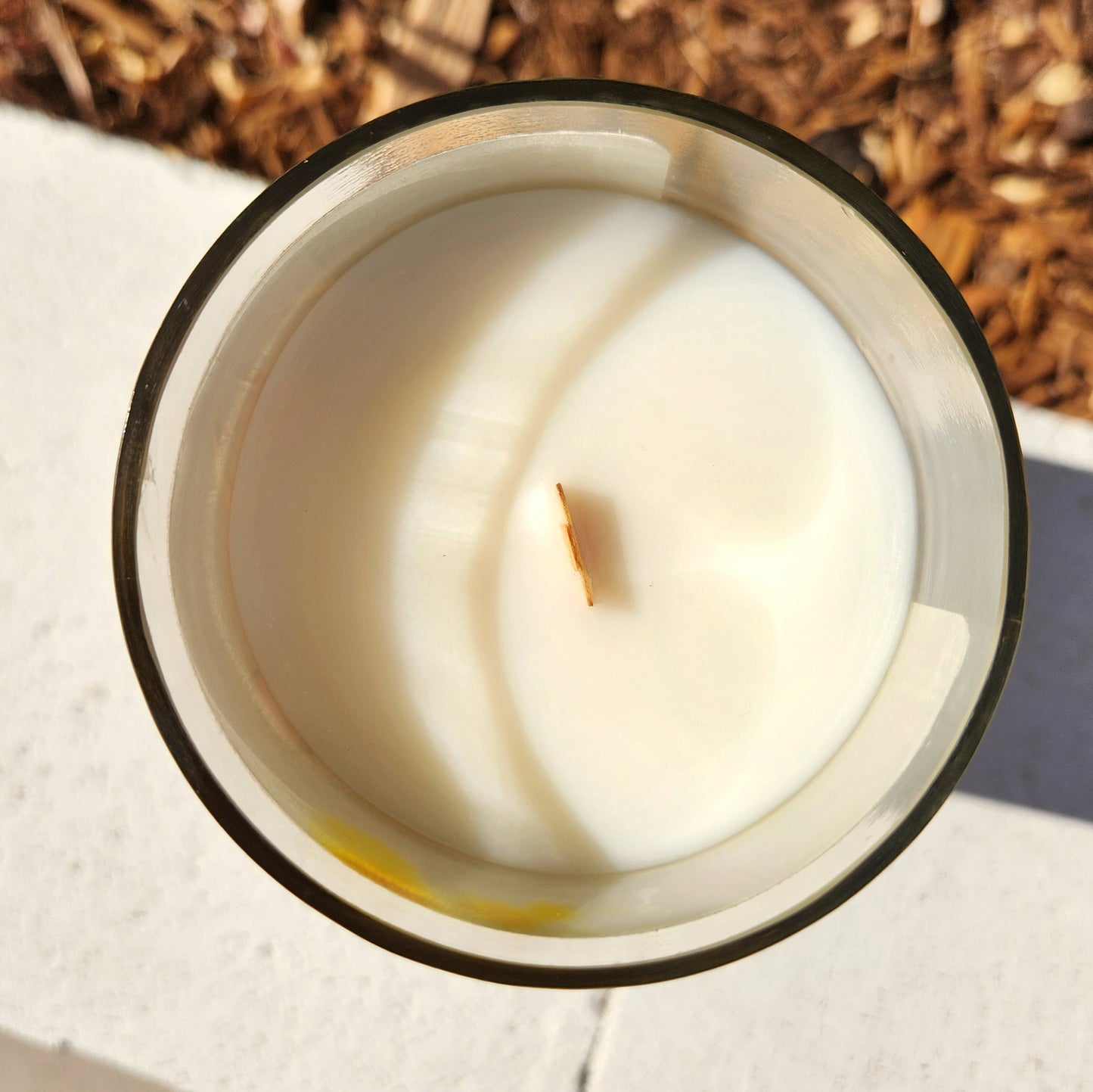 Top-down view of a Dance France coconut soy candle with a centered wooden wick and smooth, even wax surface inside a repurposed wine bottle.