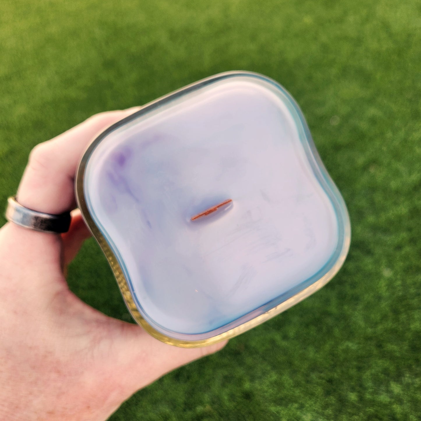 Top view of an eco-friendly coconut soy wax candle in a recycled Arizona Diamondbacks glass with a wooden wick, showcasing subtle purple and teal swirls that reflect the team’s throwback color palette.