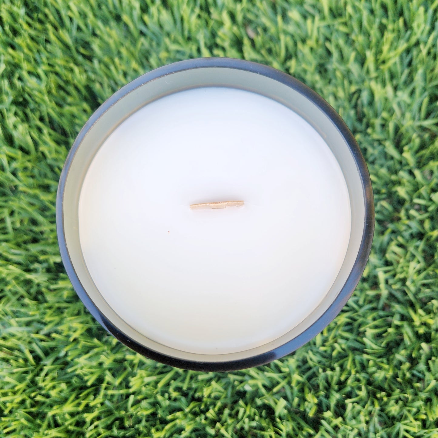 Top-down view of an unlit, hand-poured coconut soy wax candle with a wooden wick. The smooth white wax sits cleanly inside a repurposed wine bottle vessel, showcasing the even pour and eco-conscious design.