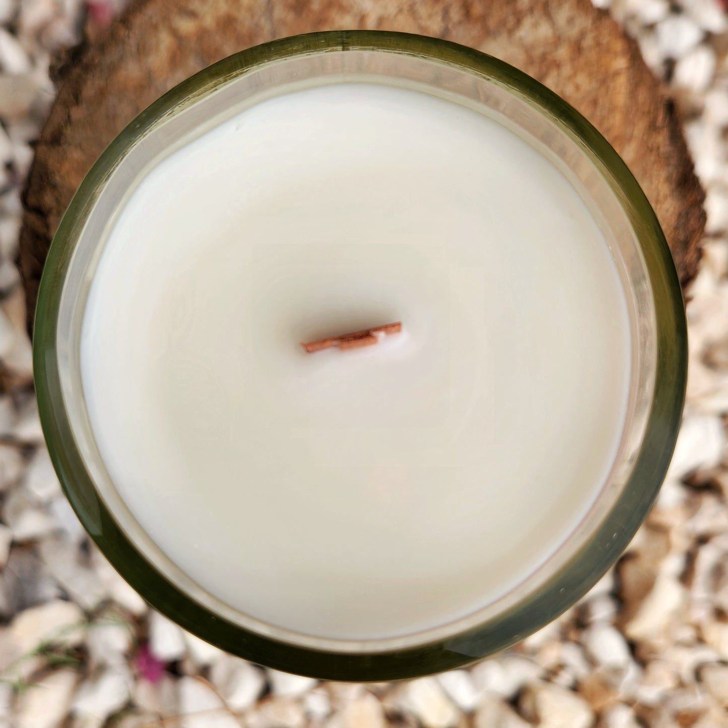 Top-down view of an eco-friendly wine bottle candle featuring a centered wooden wick and silky white coconut soy wax, housed in a repurposed clear glass vessel with a clean, polished rim.