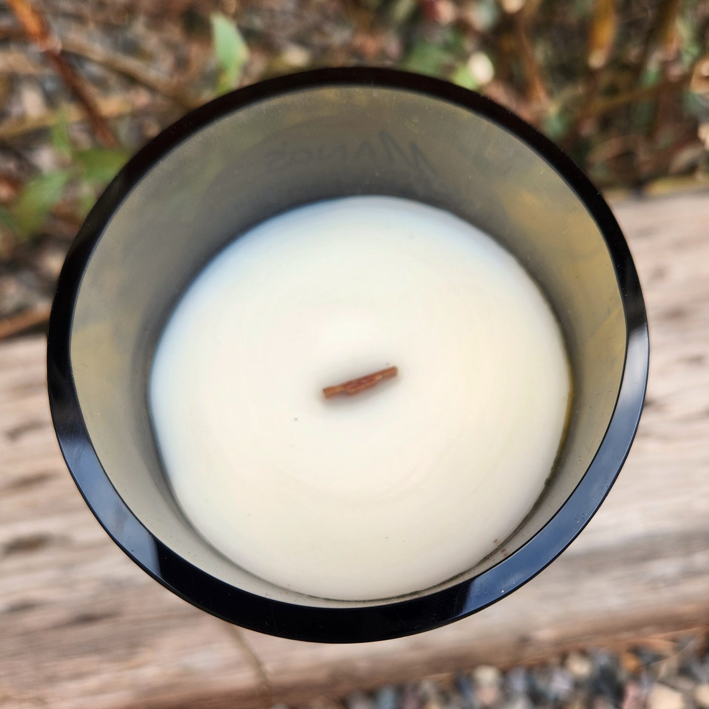 Top-down view of a clean-burning coconut soy wax wine bottle candle with a wooden wick, poured into a recycled dark glass bottle featuring subtle Día de los Muertos-style sugar skull detailing.