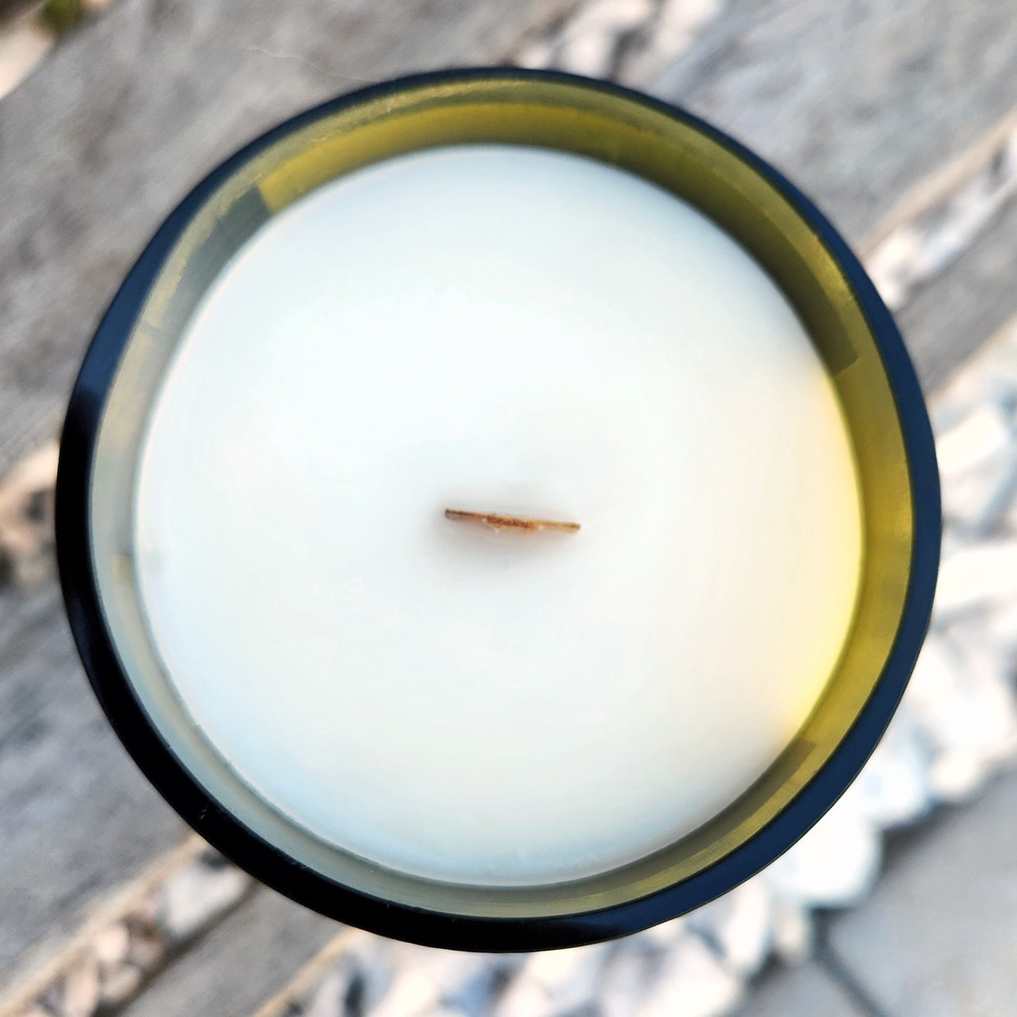 Top-down view of the “Black Hole” wine bottle candle featuring clean, creamy coconut soy wax and a centered wooden wick in an upcycled green glass vessel.