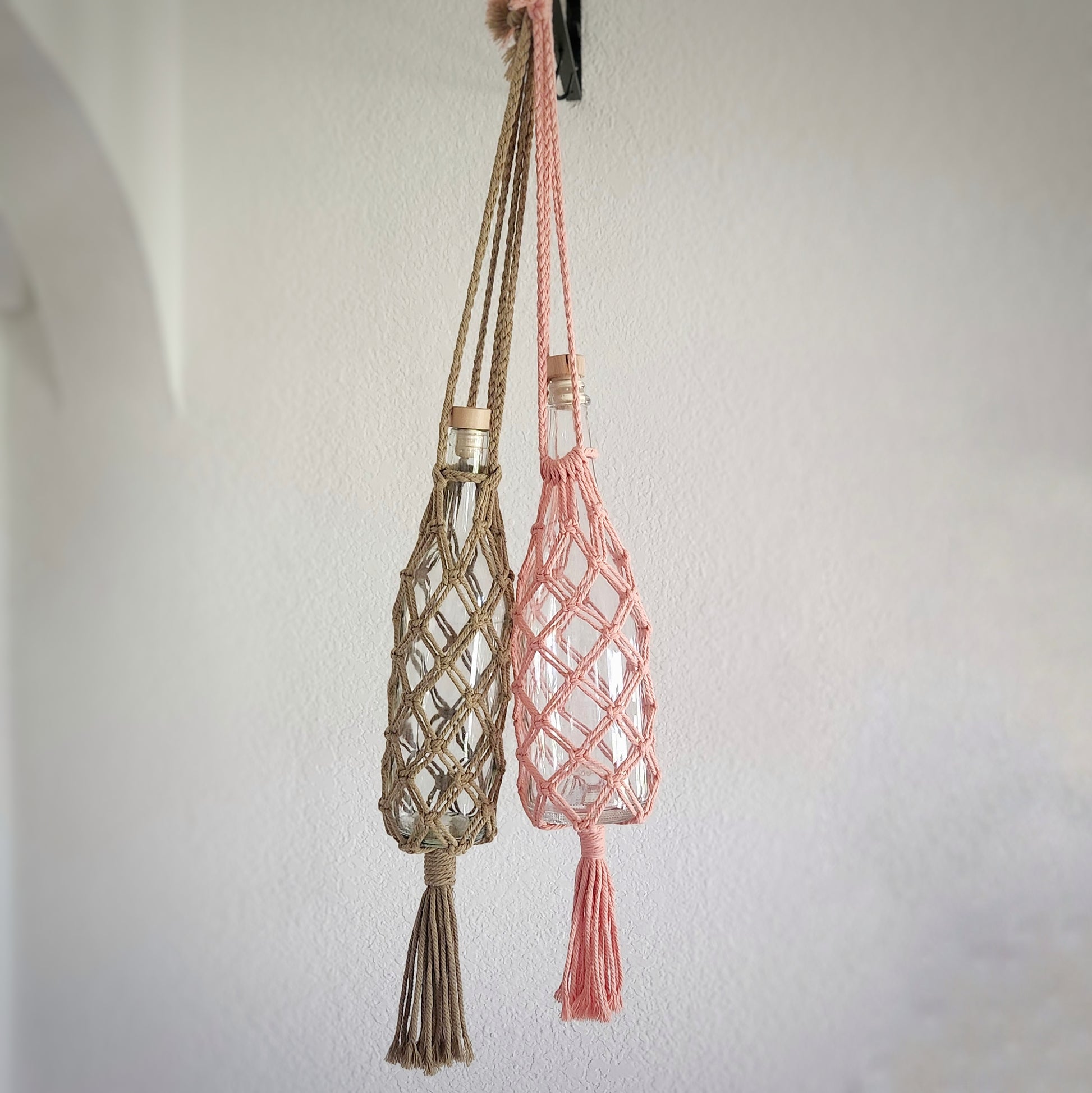 Macrame wine bottle tote bags hanging on a wall hook, displaying the versatile and stylish design perfect for carrying wine bottles.