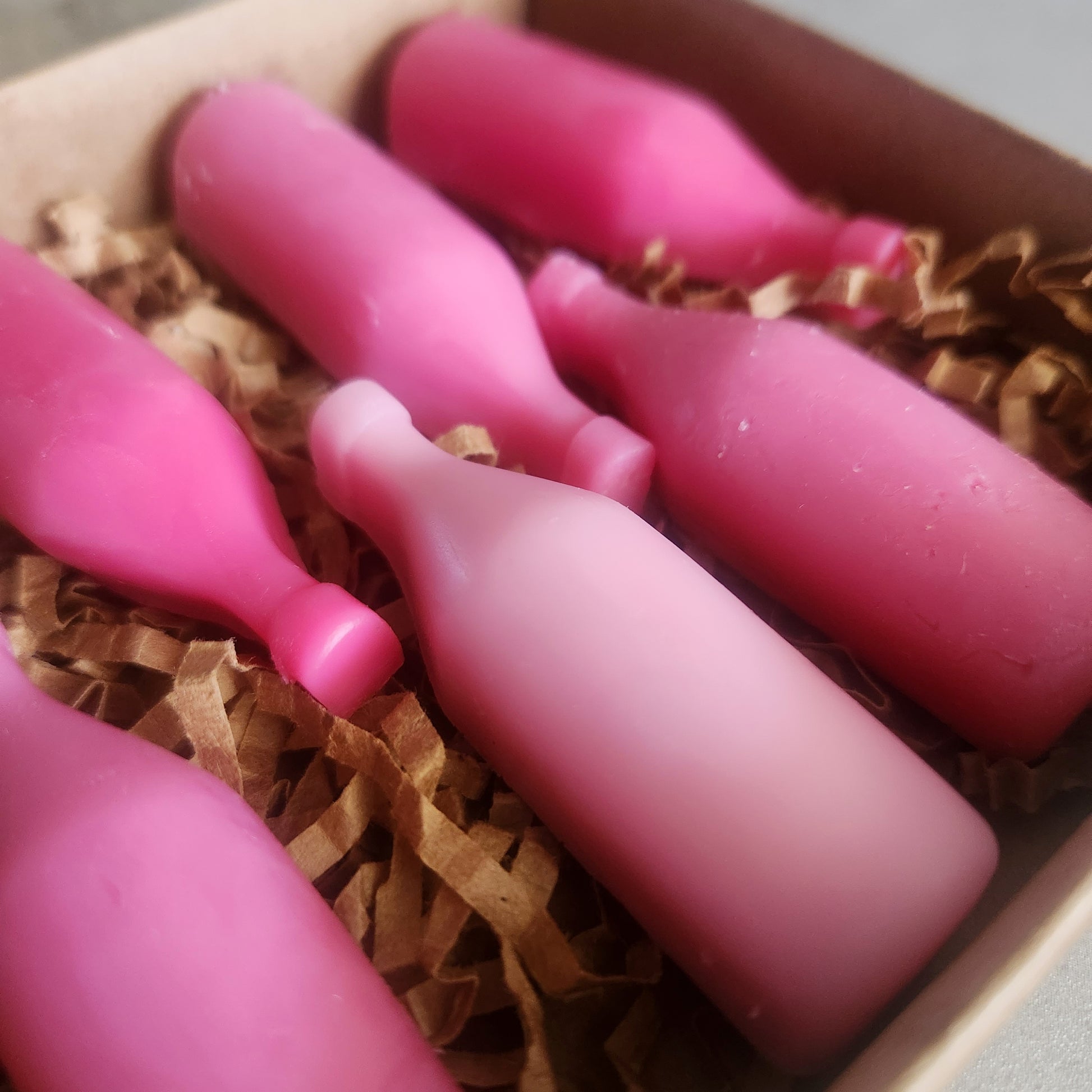 Detailed view of "Strawberry Wine" wax melts, showcasing the various shades of pink in wine bottle shapes.