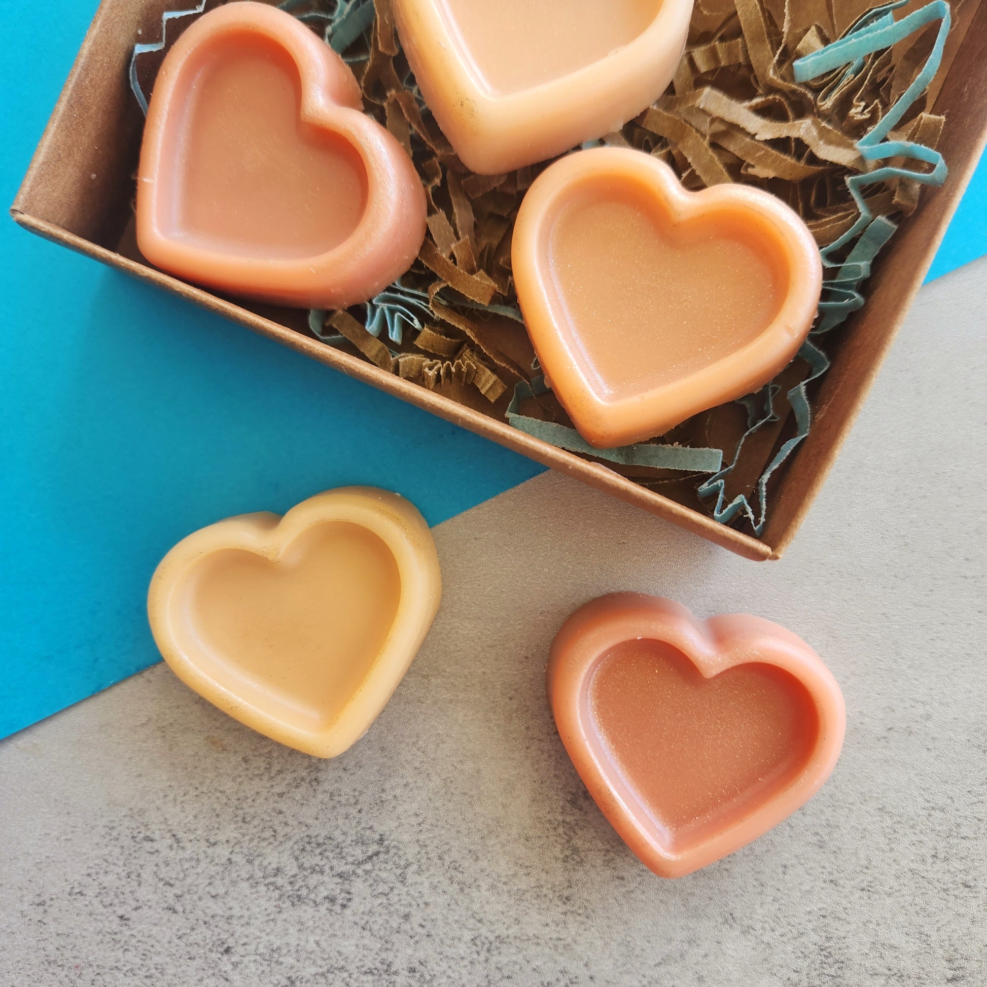 Close-up of Sonoran Rain heart-shaped wax melts in a box with earthy brown and blue crinkle paper, capturing the warm, creosote-inspired scent.