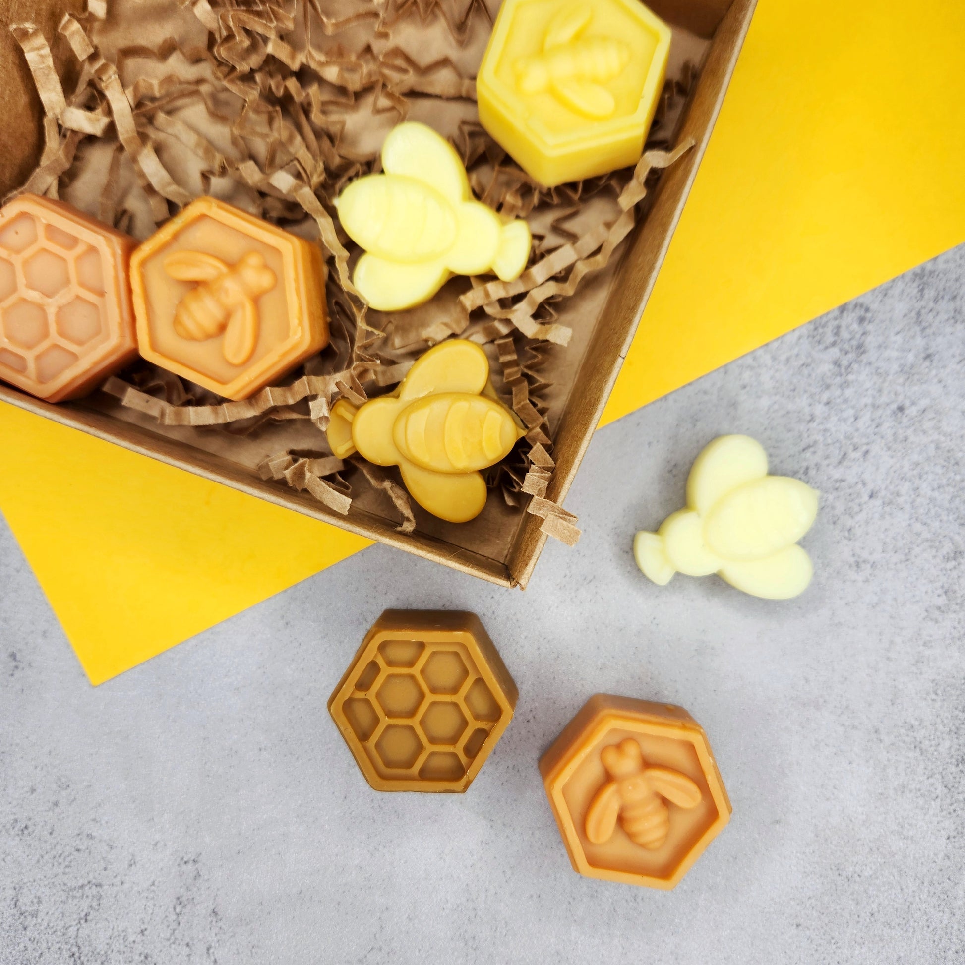 Close-up of Goldwater Spiced Honey Vanilla wax melts shaped like bees and honeycombs, displayed in eco-friendly packaging.