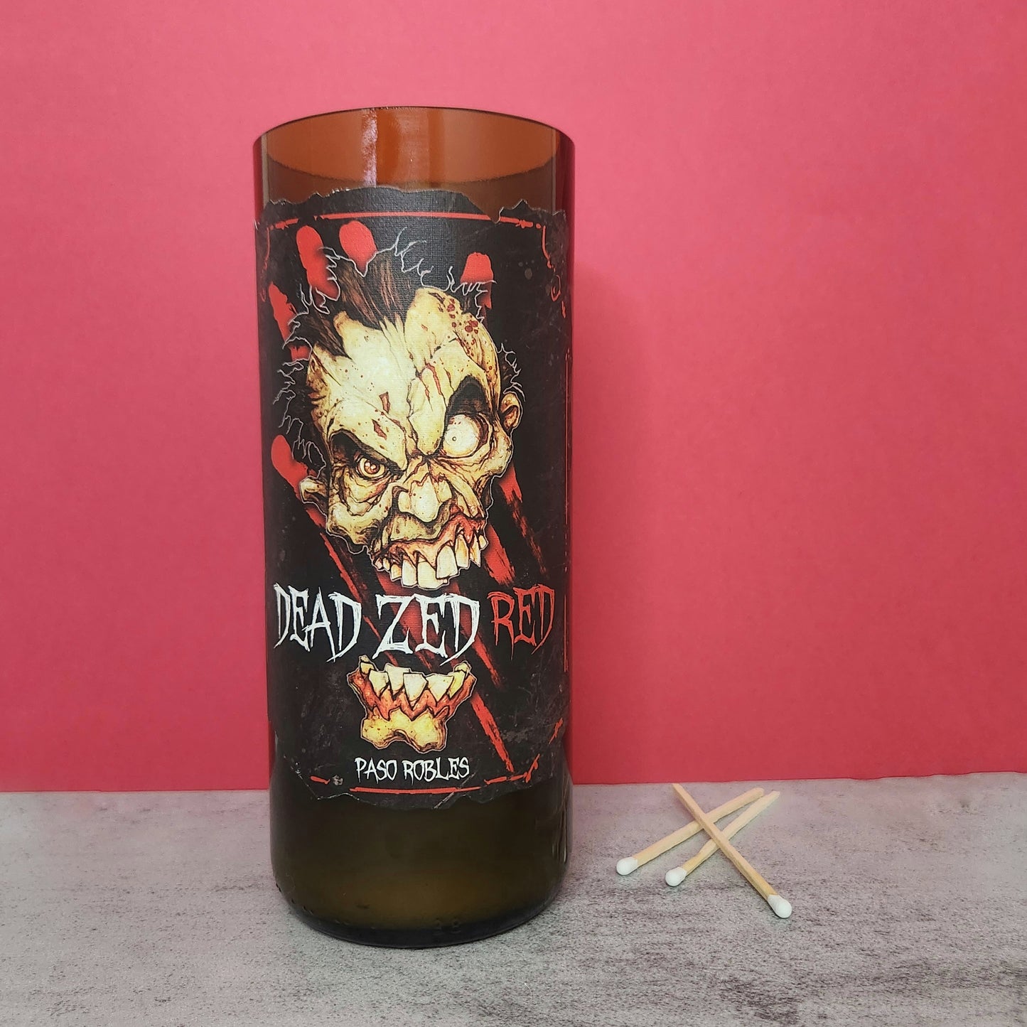 Front view of the Dead Zed Red wine bottle candle, featuring a spooky zombie design on the label, perfect for Halloween decorations or horror-themed home decor.