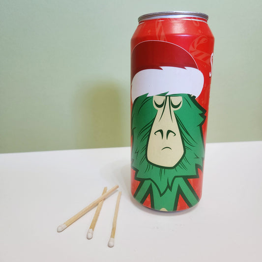 Hand-poured Peppermint Chocolate scented candle in a 14oz recycled Arizona beer can featuring a festive Grinch-inspired holiday design. Made with eco-friendly coconut-soy wax and a wooden wick for a sustainable and cozy holiday experience