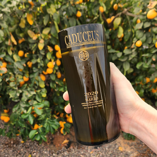 Featuring a recycled Caduceus wine bottle candle, hand-poured with sustainable coconut soy wax. Set against a vibrant orange tree backdrop, this unique piece highlights Arizona's charm and sustainability.