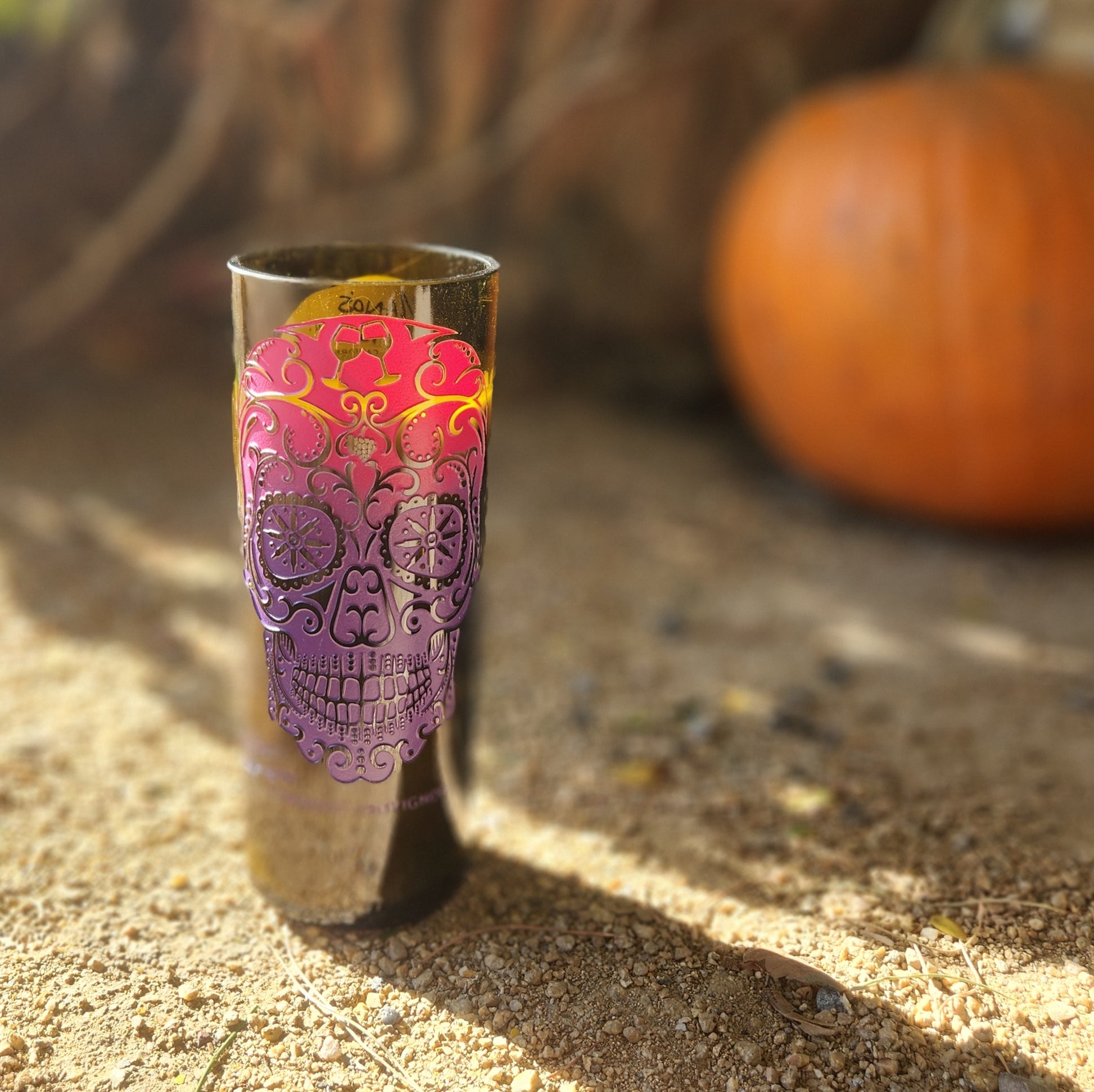 Add vibrant seasonal flair with this hand-poured candle in a recycled wine bottle. Featuring a colorful sugar skull design and set against a rustic autumn scene with a pumpkin, it’s perfect for celebrating fall and Día de los Muertos