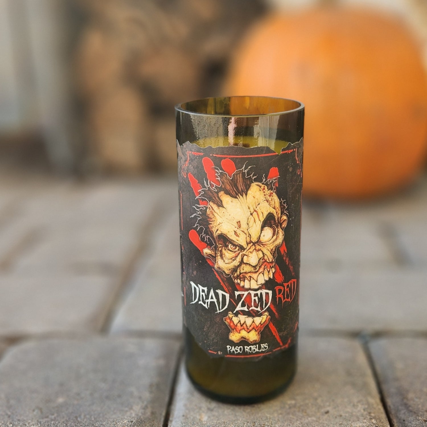 Set a haunting tone with this hand-poured candle in a recycled Dead Zed Red wine bottle. Featuring a chilling zombie design and set against an autumn backdrop with a pumpkin, it’s the perfect spooky decor for Halloween and beyond.