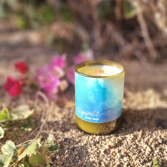 This serene candle is housed in a recycled wine bottle with a calming blue 'Upwell Pinot Noir' label, evoking the tranquility of ocean waves and fine wine.