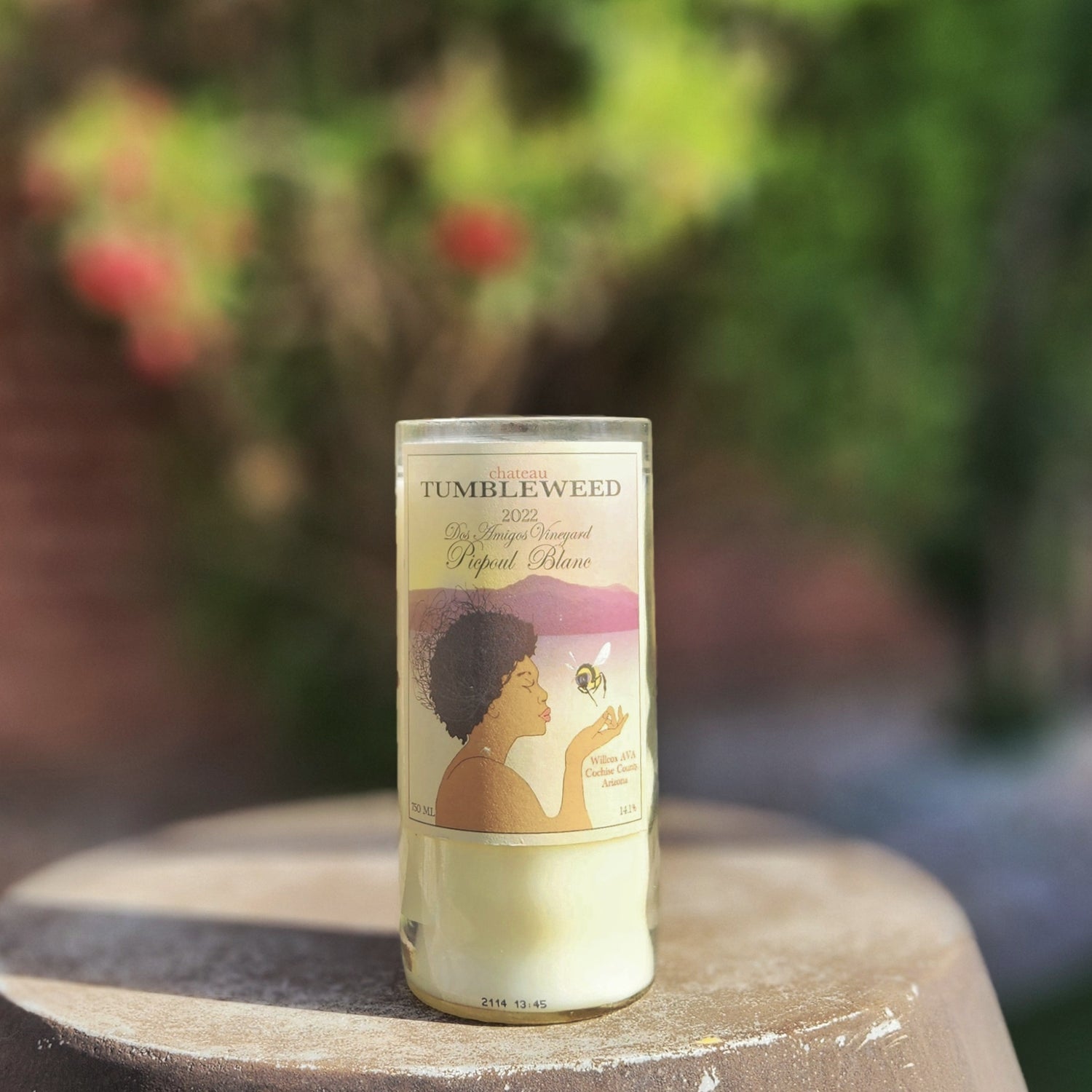 Delight in sustainability and elegance with this hand-poured candle in a recycled Chateau Tumbleweed bottle. Featuring the serene Picpoul Blanc label design of a woman and a bee, it brings a touch of nature and artisanal charm to your home