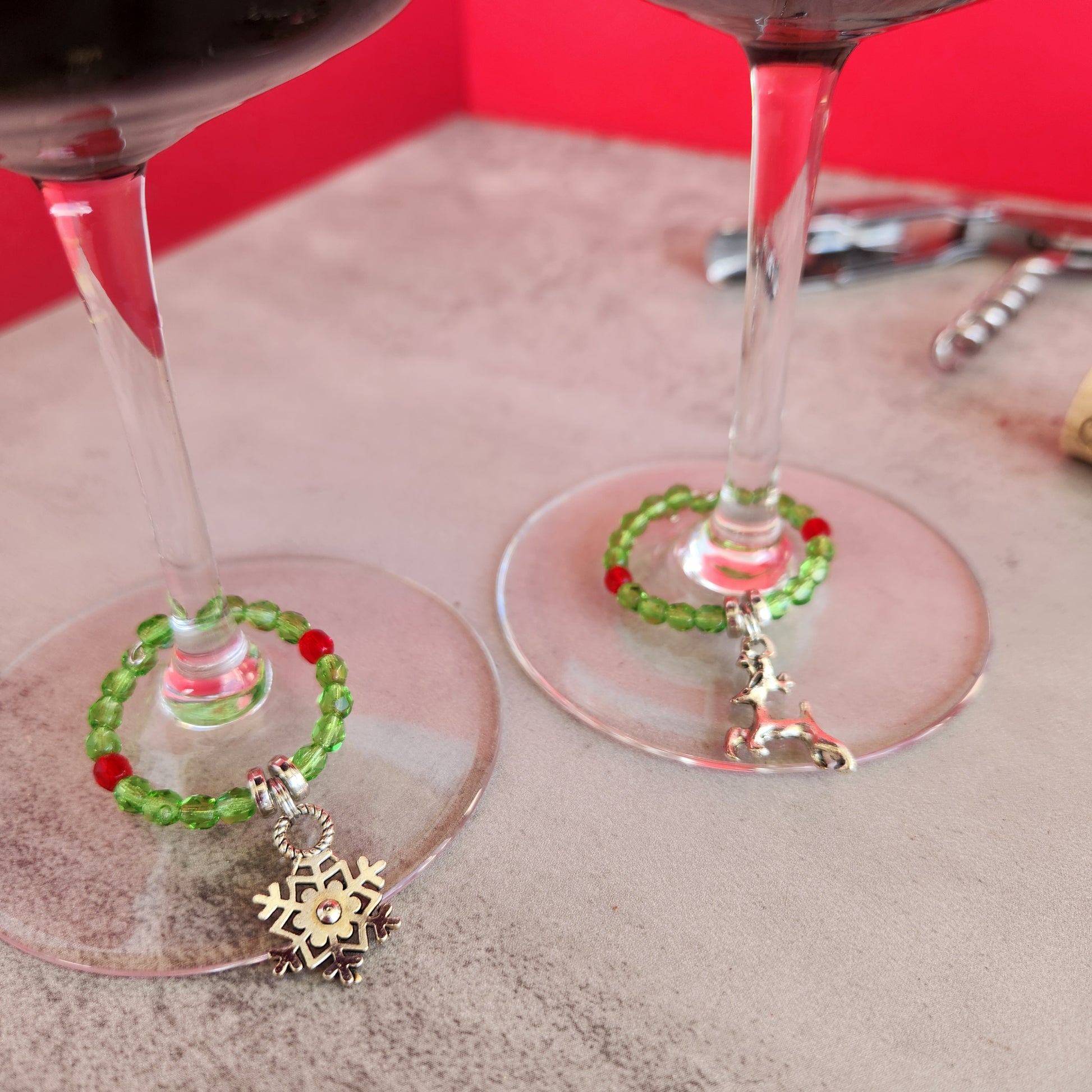 Close-Up of Two Wine Glass Charms with Red and Green Beads and Silver Charms Including Reindeer and Snowflake, for Christmas Celebrations