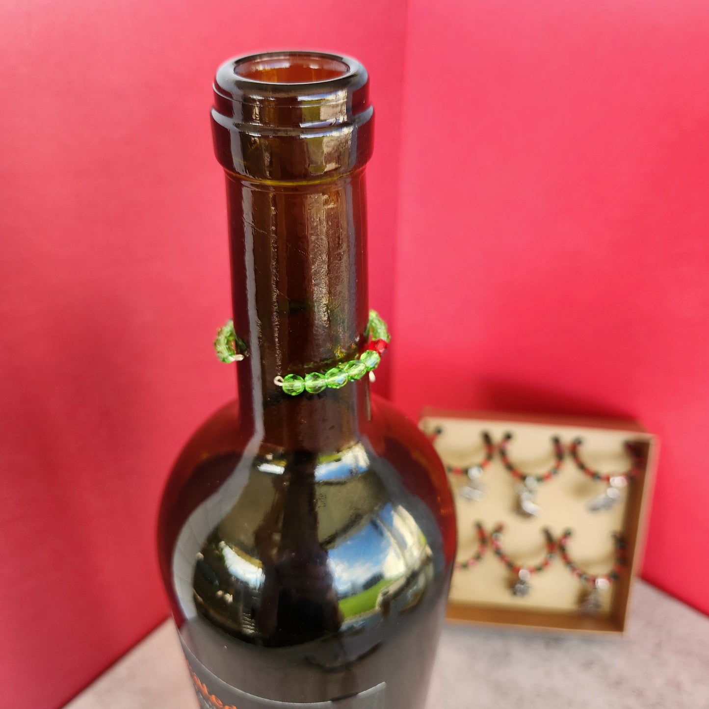 Close-Up of Christmas Wine Glass Charm on a Wine Bottle, Featuring Red and Green Beads with a Silver Reindeer Charm for Holiday Parties