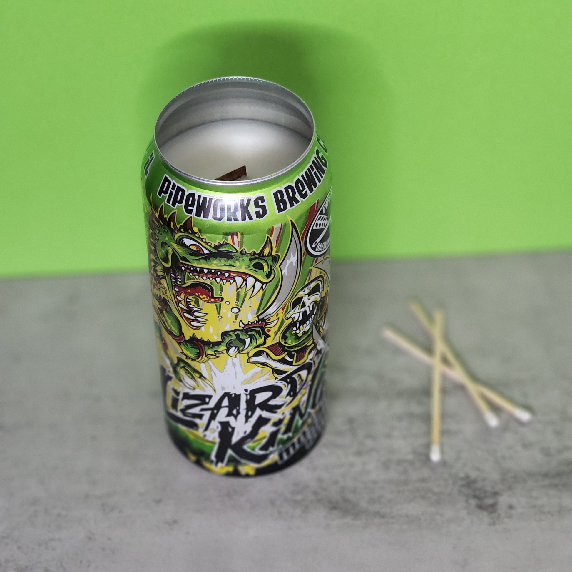 Front angle view of a Bourbon Lime scented candle in a recycled Lizard King beer can, featuring vibrant comic-style artwork and a recycled material design, perfect for eco-conscious consumers.