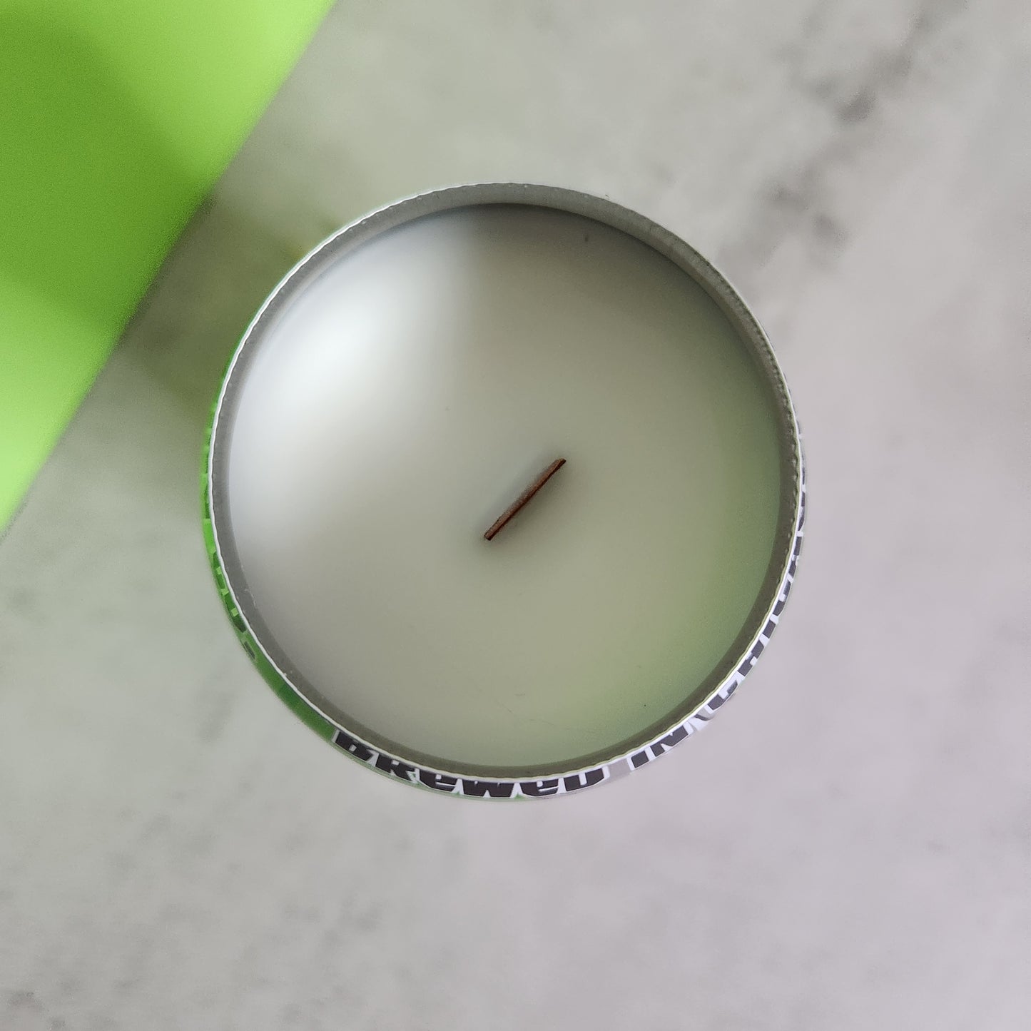 top view of the Bourbon Lime scented candle with a wooden wick, nestled in a recycled Lizard King beer can, showing the clean, smooth surface of the candle and the unique recycled can design.