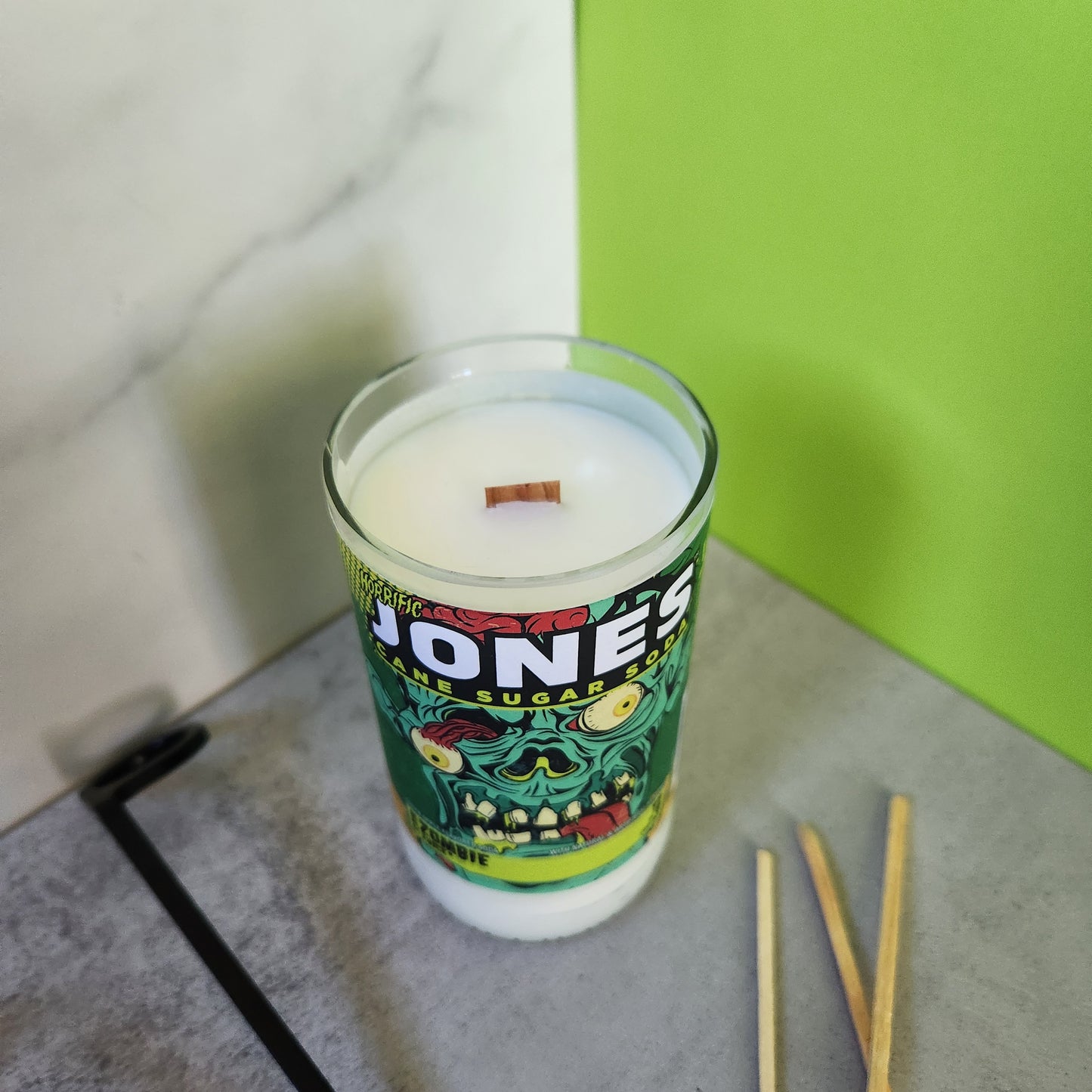 Eco-friendly coconut-soy wax candle in a recycled Jones soda bottle with spooky zombie label, perfect for Halloween decor and seasonal vibes.