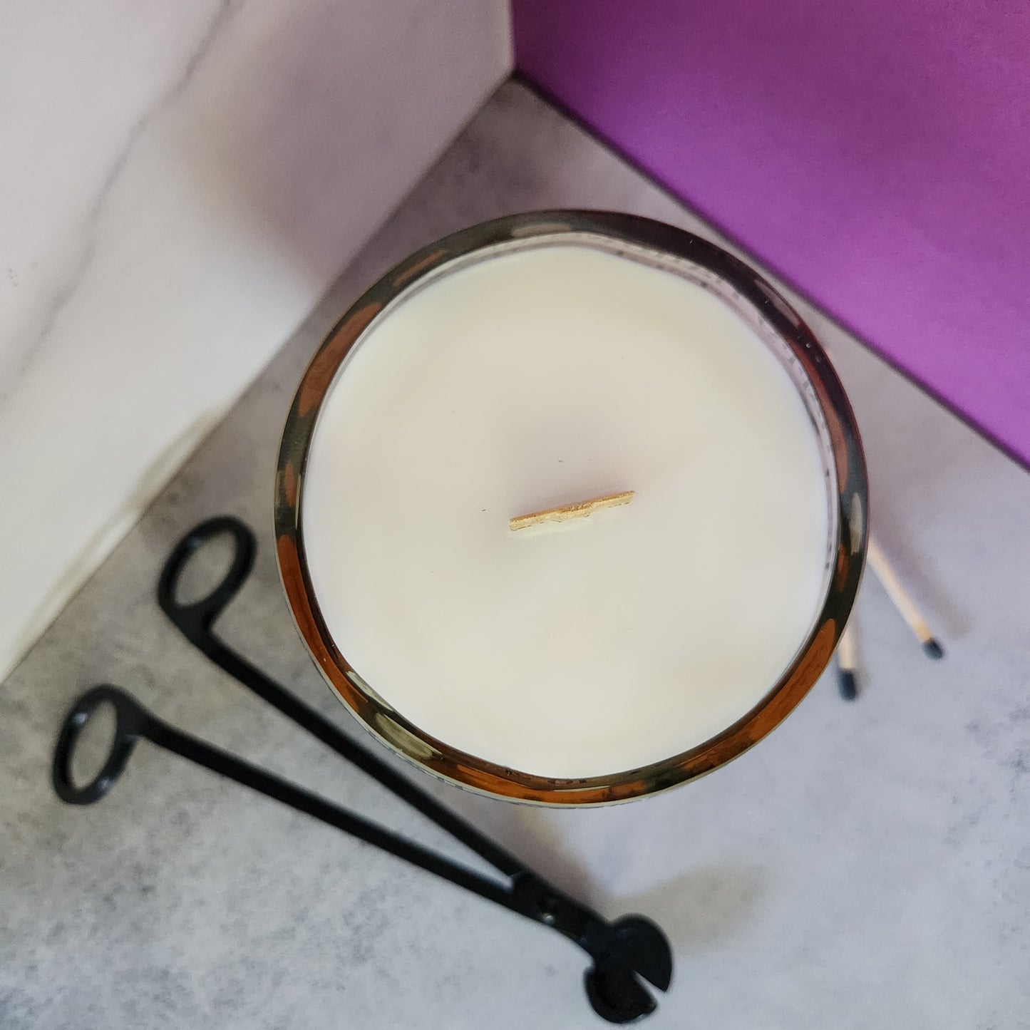 Top view of an unlit Caramel Apple scented Halloween-themed wine bottle candle, highlighting the wooden wick, shiny smooth glass rim, and sustainable, eco-conscious design.