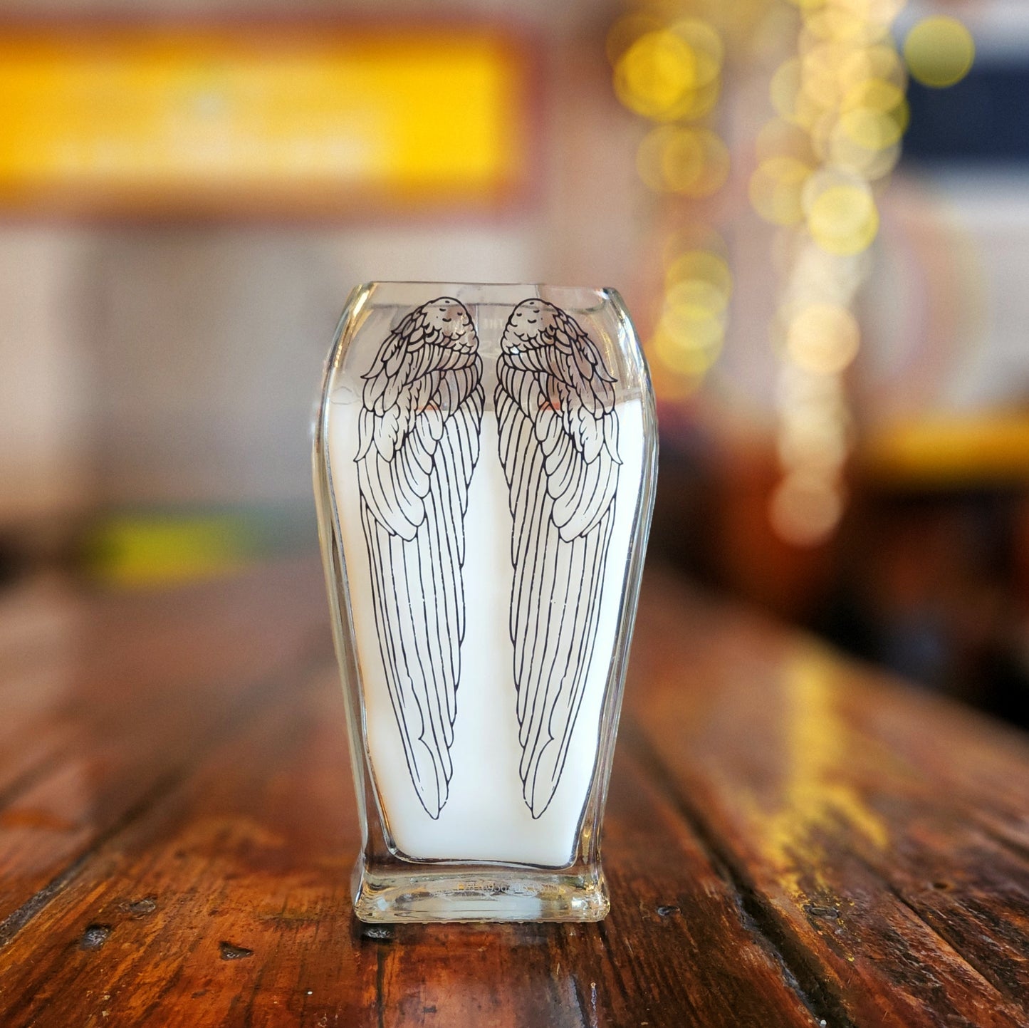 Back view of an upcycled Angel’s Envy bottle candle with an etched wing design and dual wooden wicks, capturing the artisanal charm of this eco-friendly candle made from glass.

