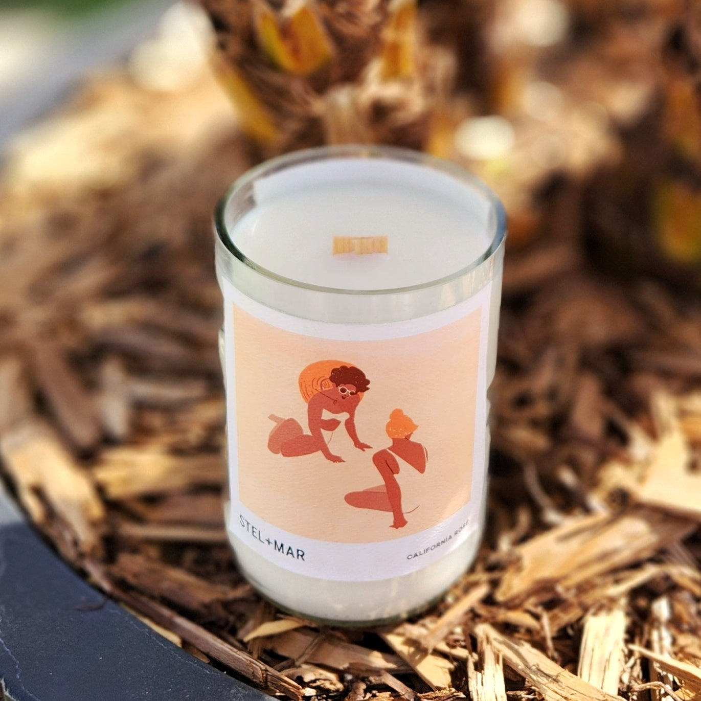 Angled top view of a handmade recycled wine bottle candle with coconut soy wax and a wooden wick, offering a sustainable and non-toxic burn.