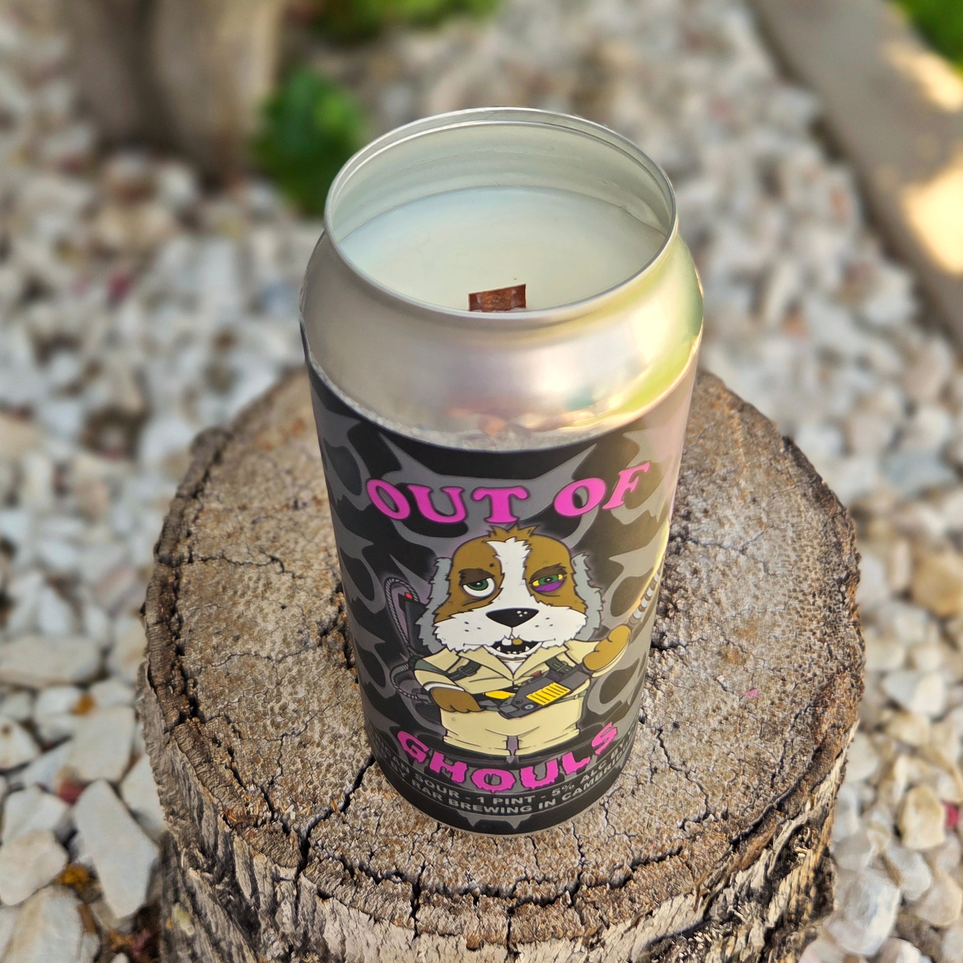A handmade beer can candle in a recycled can featuring a Ghostbusters-inspired cartoon dog in a beige jumpsuit, holding a ghost trap and looking unimpressed. This coconut soy wax candle is a fun, clean-burning piece of spooky decor.