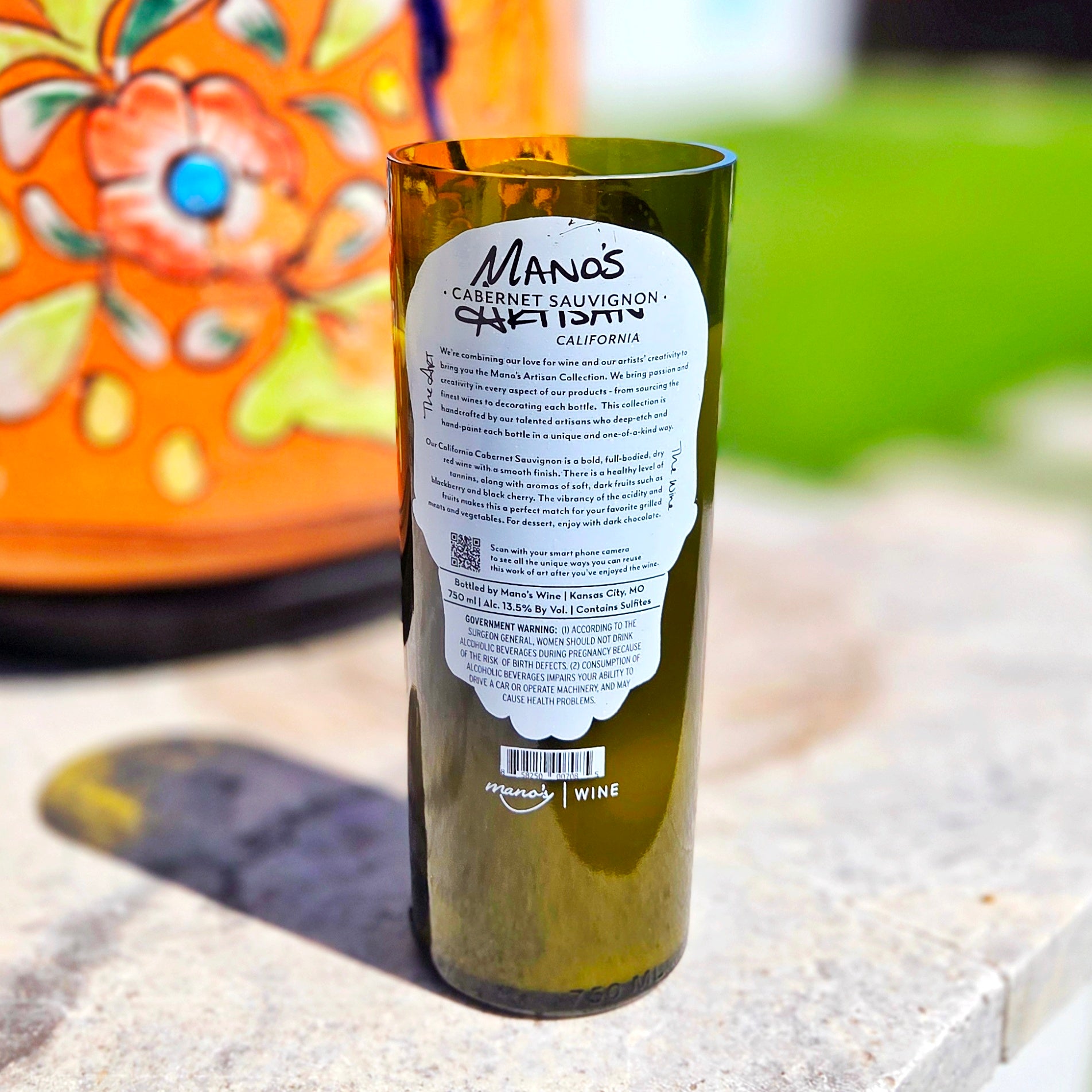 Rear view of a recycled wine bottle candle displaying the original Manos Cabernet Sauvignon label, emphasizing the upcycled craftsmanship and sustainable design of this eco-friendly home decor piece.