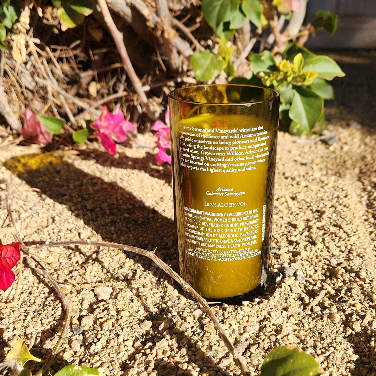 Back of a green Arizona Stronghold wine bottle candle, showing the vineyard’s label and bold white lettering. This clean-burning candle is hand-poured with coconut soy wax and features a charming recycled finish.